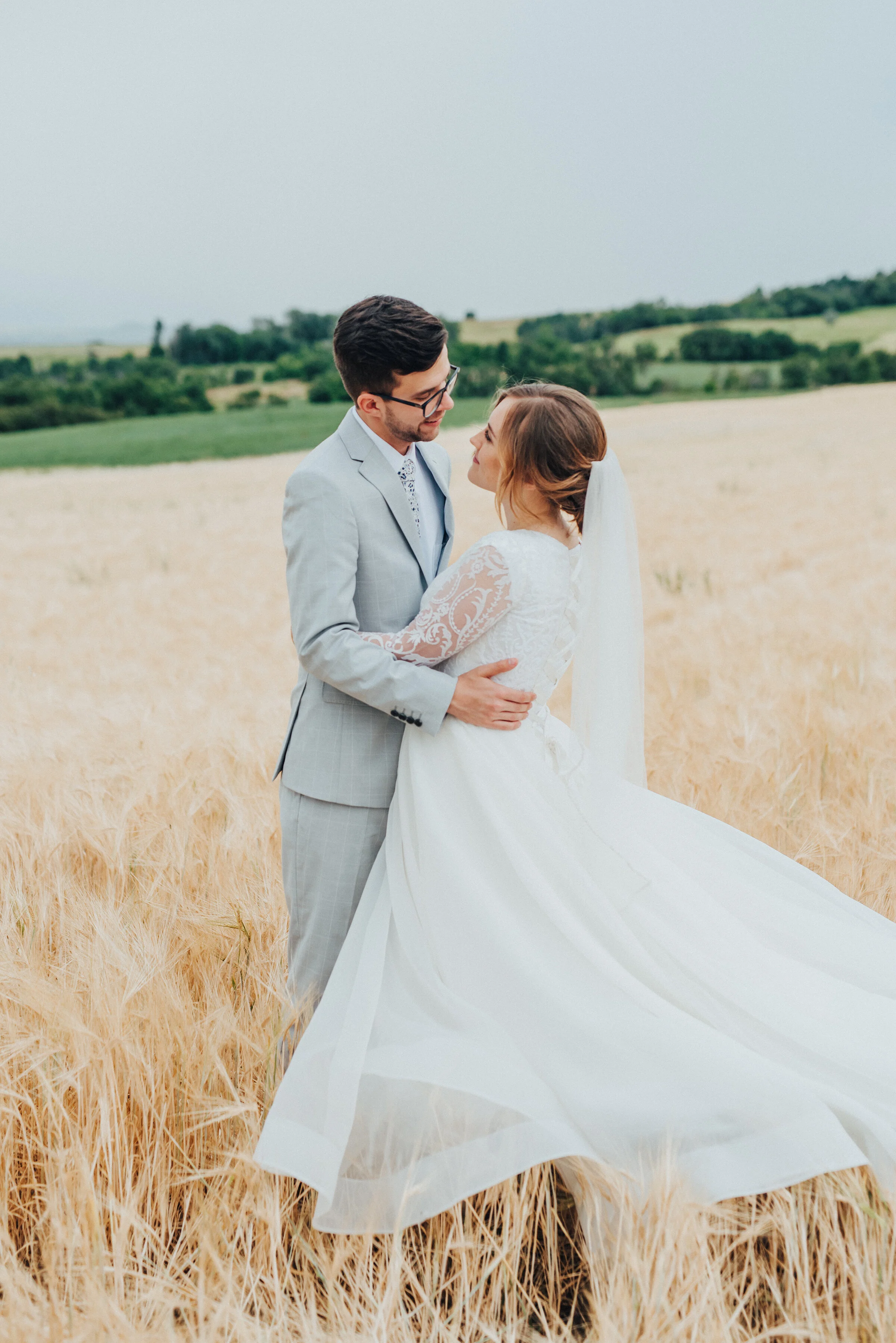  Singing (or dancing) in the rain! This bridal session shot by Kristi Alyse Photography captures romance, playfulness and movement amongst the vast fields of Mendon, Utah. slow dancing bridal portraits, flowing ball gown dress, light gray wedding sui