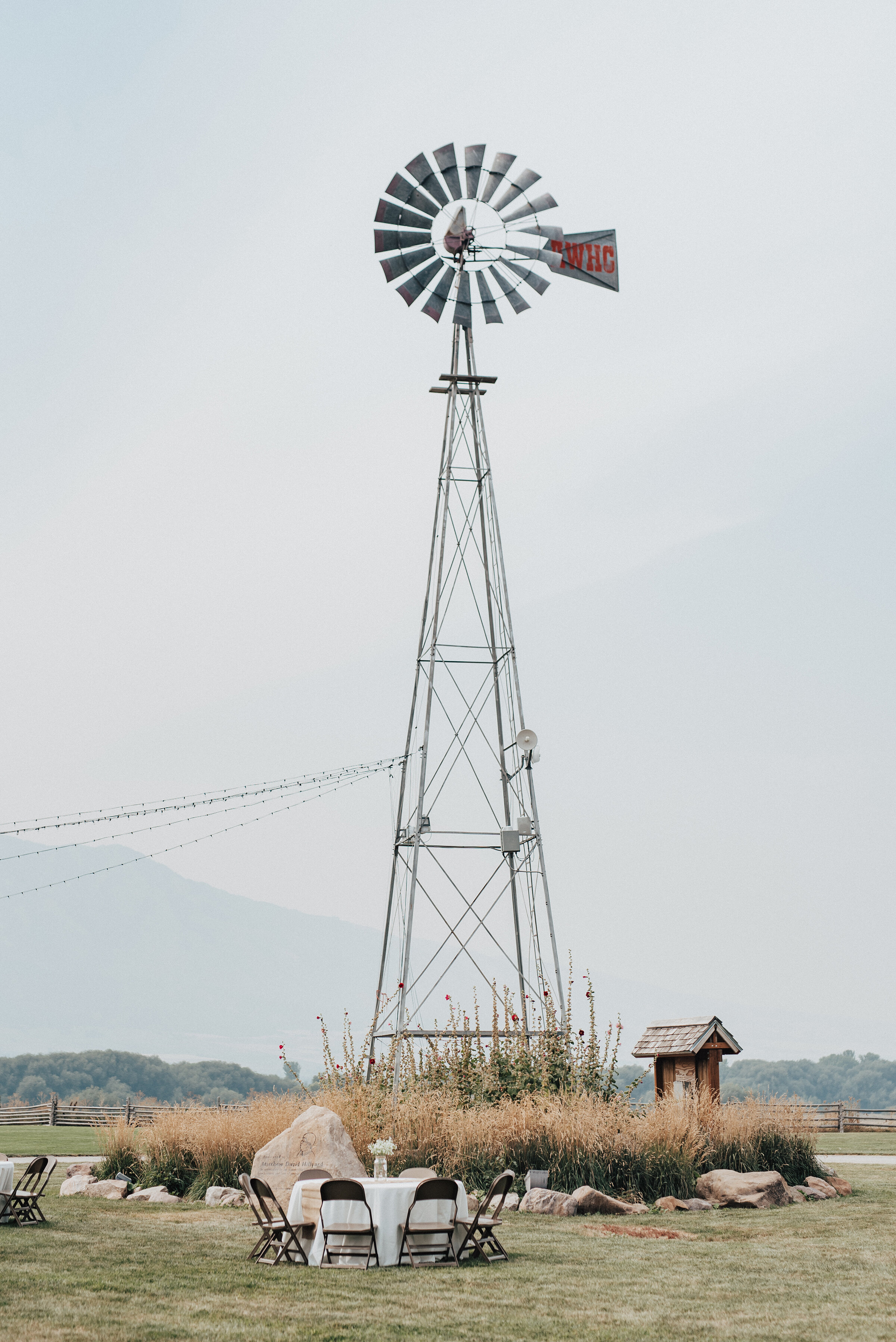 A southern charm styled outdoor wedding reception held on a ranch in Logan, Utah and shot by Kristi Alyse Photography overlooks mountains and windmills. windmill, ranch outdoor wedding reception, white tablecloth wedding tables, mountain wedding, lo