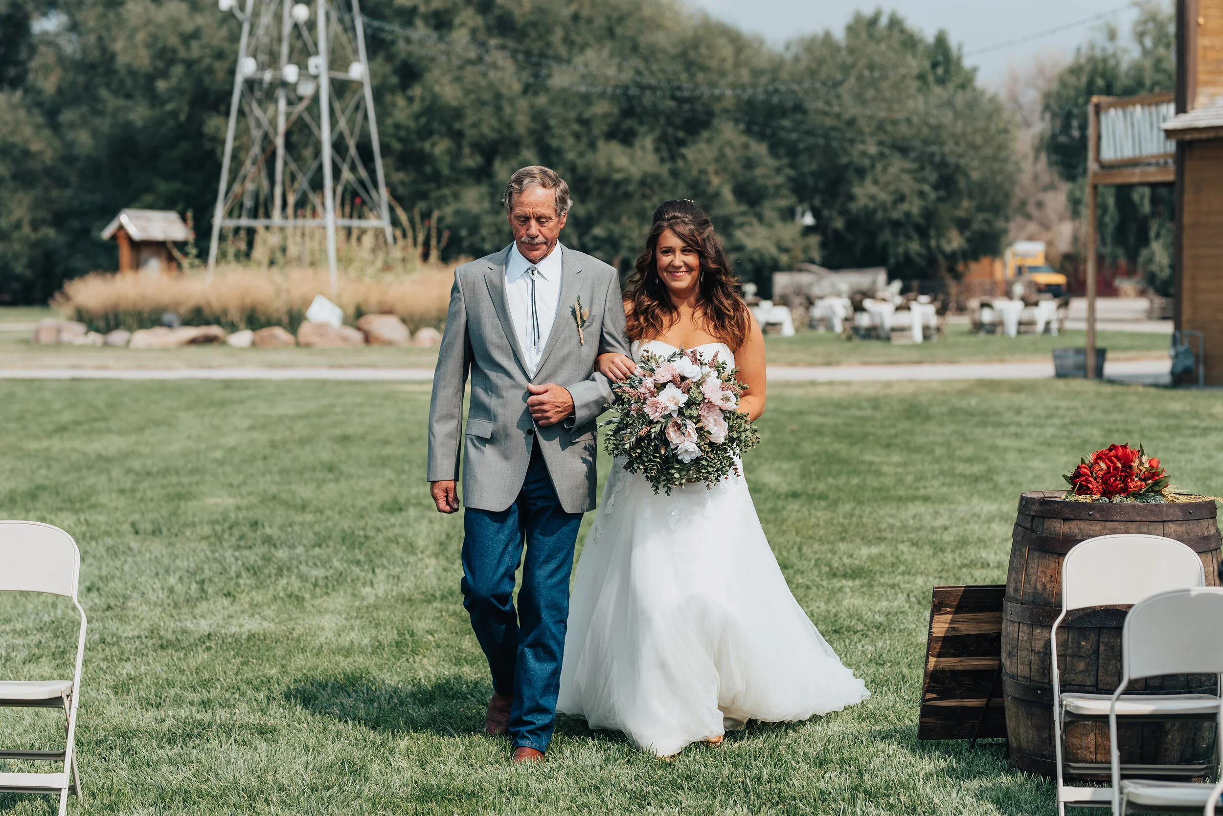 With elements of the perfect southern wedding in the backdrop, Kristi Alyse Photography captures a beaming bride makes her way down the isle with her father in Logan, Utah. outdoor ranch wedding, wedding isle, southern wedding attire, wedding wrangl…