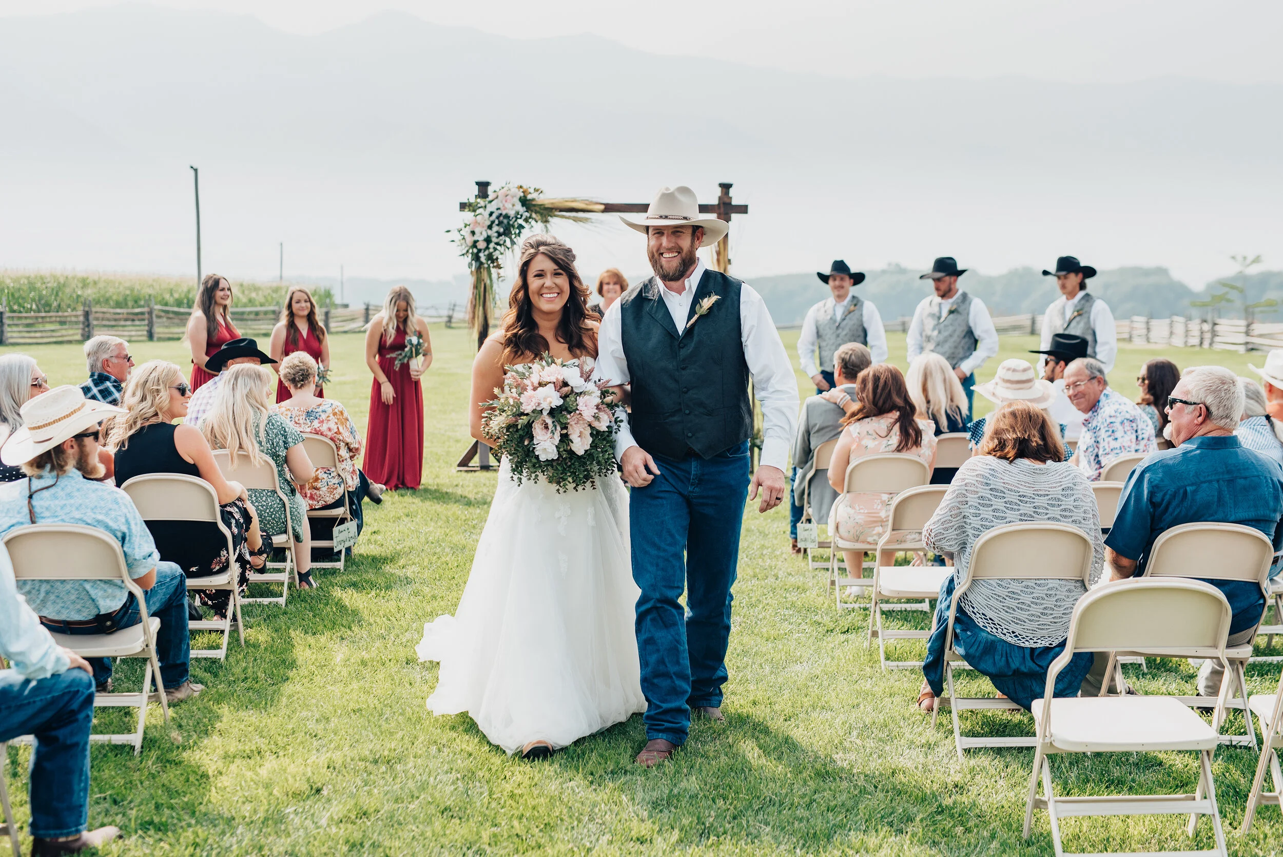  Kristi Alyse Photography  captures a blissfully wedded bride and groom walking down the isle at their gorgeous barn wedding in Logan, Utah. husband and wife wedding, walking down the isle photos, grass outdoor wedding ceremony, wood floral wedding a