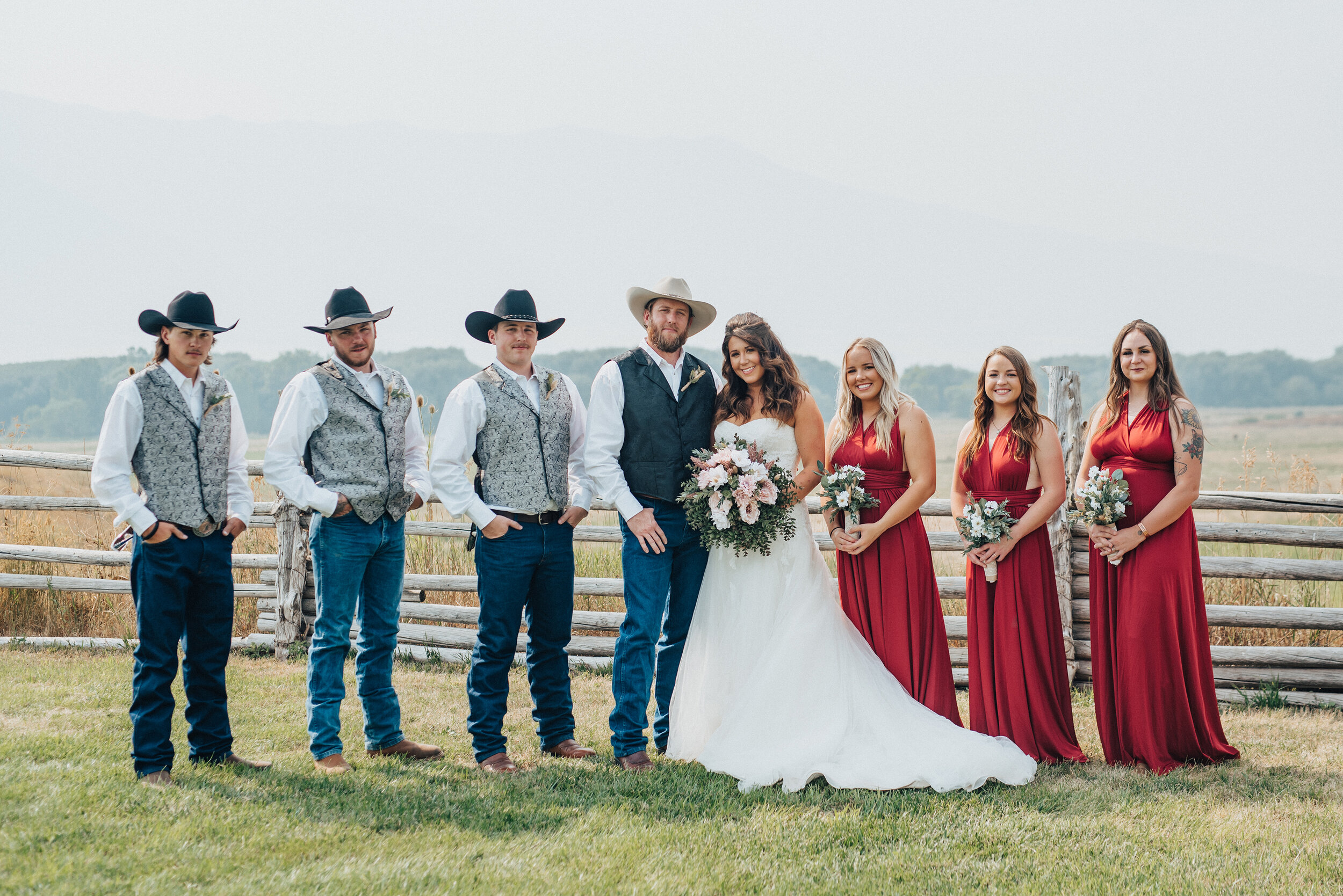  The happily wedded bride and groom along with their bridal party pose with picturesque mountains and vast fields in the backdrop of their wedding formals taken by Kristi Alyse Photography in Cache Valley, Utah. wrangler wedding jeans, southern weddi