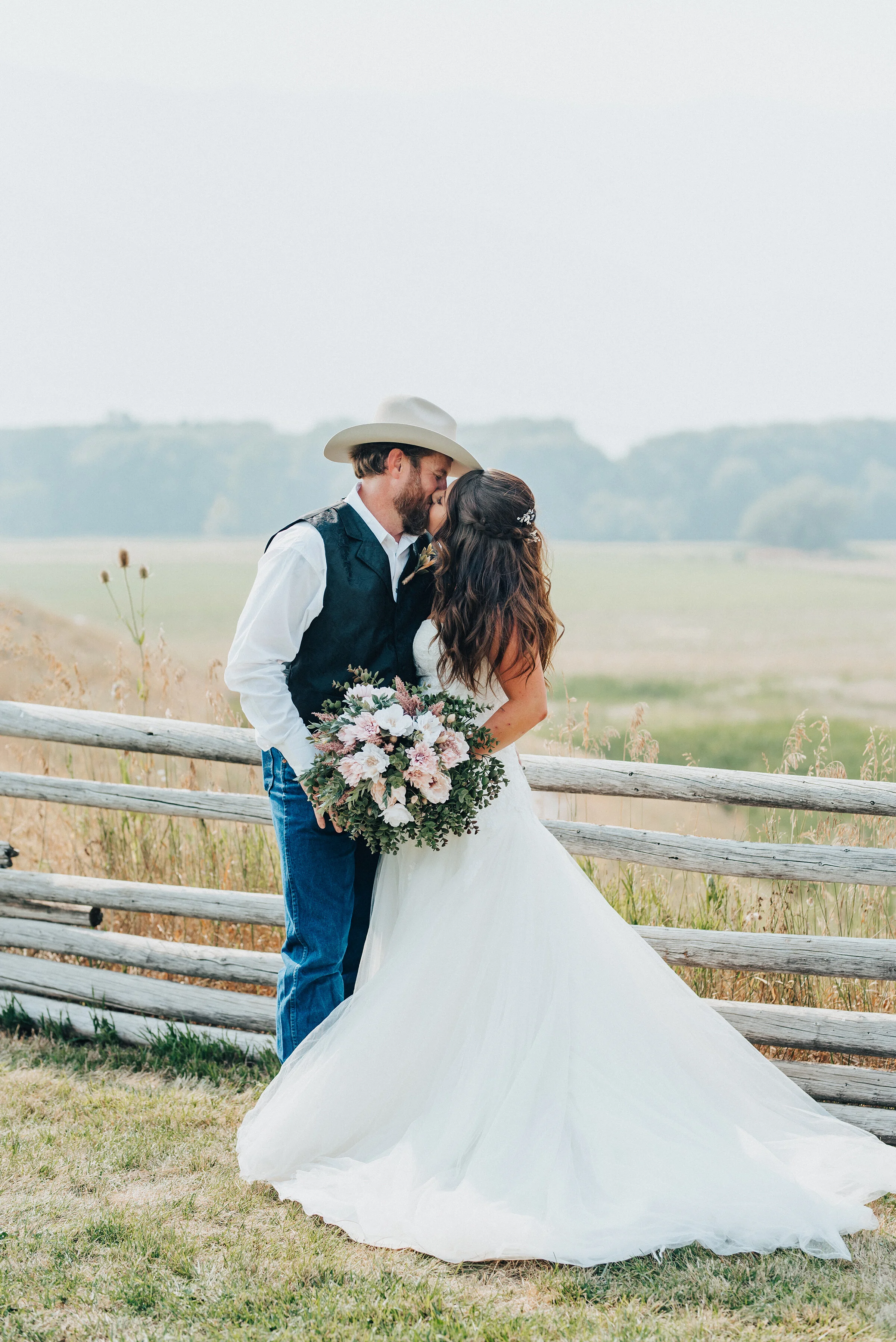  Kristi Alyse Photography captures bride and groom romantically kissing with vast fall fields and Utah mountains in the backdrop at their barn wedding in Cache Valley, Utah. bride and groom kissing, southern wedding, groom wearing wrangler jeans and 