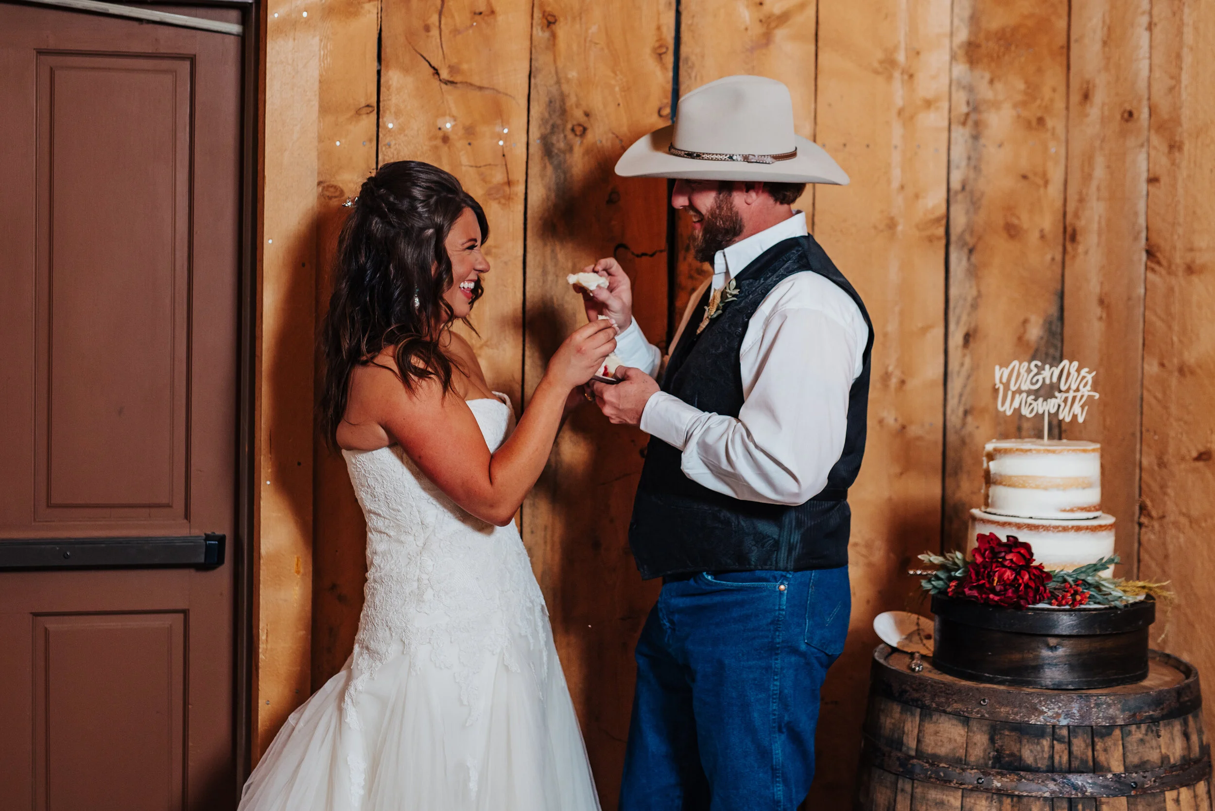  Kristi Alyse Photography captures a bridal couple mid-cake smash at their barn wedding reception in Wellsville, Utah. cake smash, wedding cake, naked wedding cake, crumb cake wedding cake, sweetheart wedding dress, wrangler jeans wedding pants, wedd