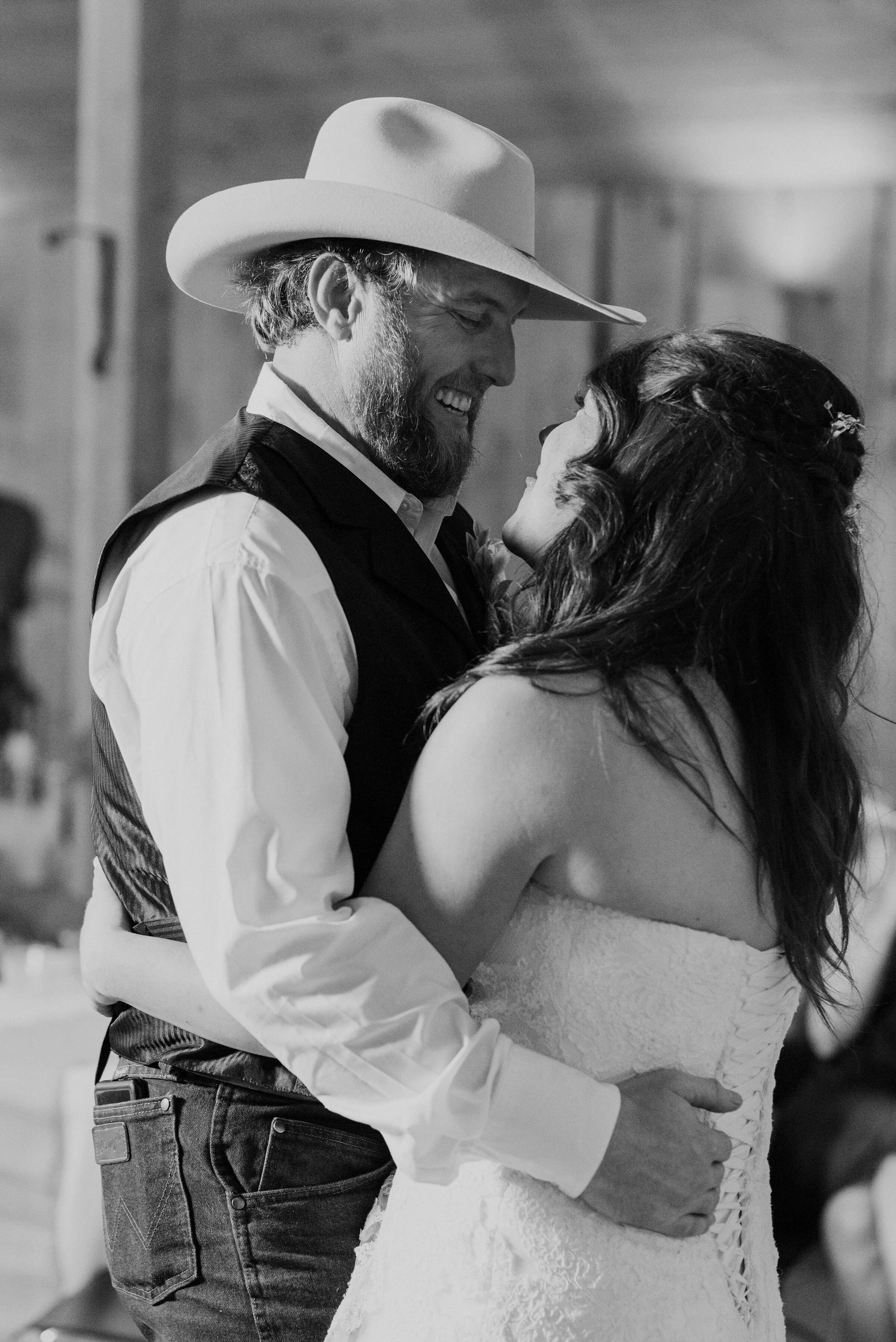 With slow western tunes in the backdrop this southern bride and groom joyously take to their first dance at their barn wedding reception in Wellsville, Utah, shot by Kristi Alyse Photography. wrangler wedding jeans, laced up strapless wedding dress,…