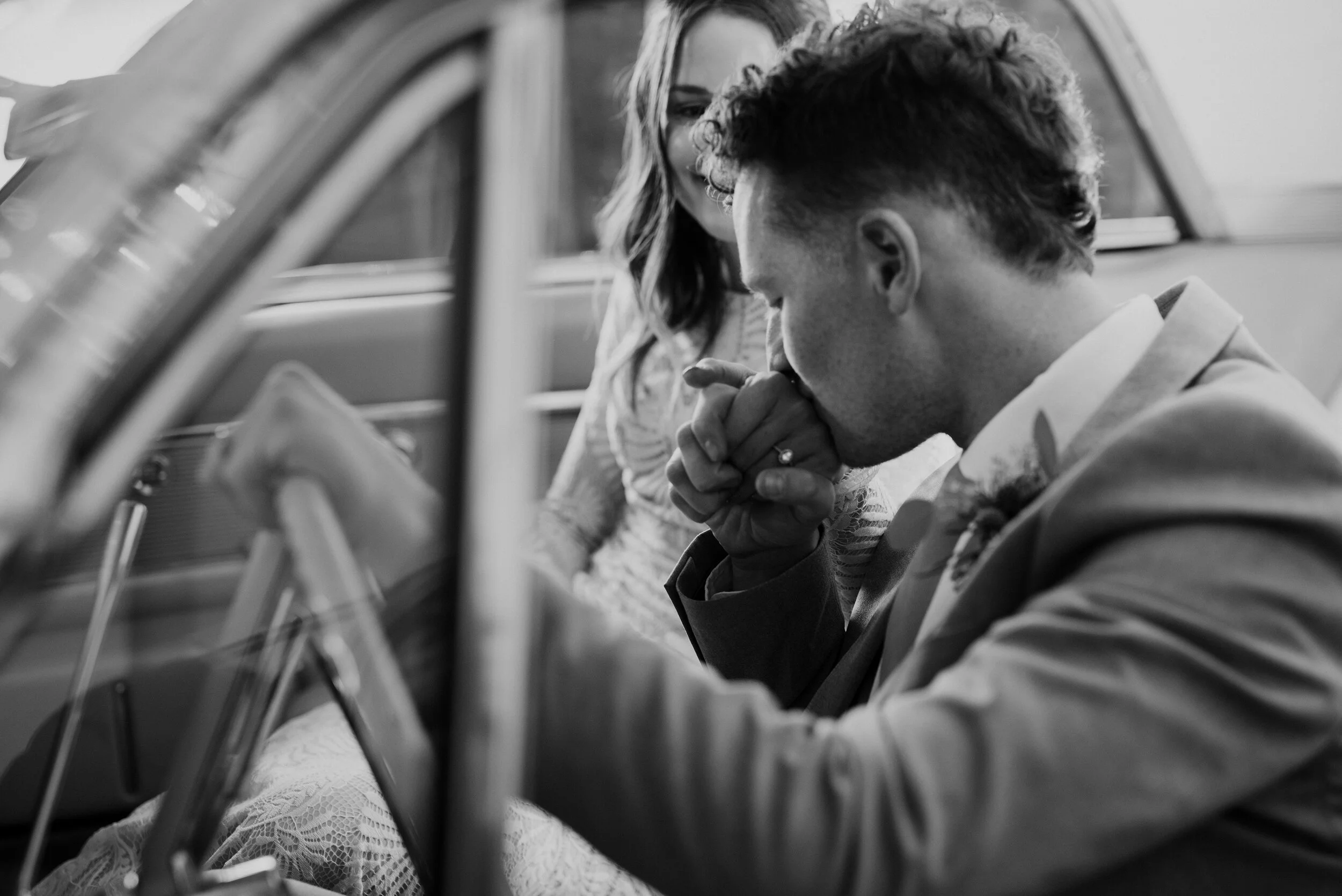 Blissfully married and having escaped to their getaway car, Kristi Alyse Photography captures quiet moments between bride and groom driving off in their vintage car. groom kissing brides hand, vintage getaway car, wedding reception exit, bohemian st…