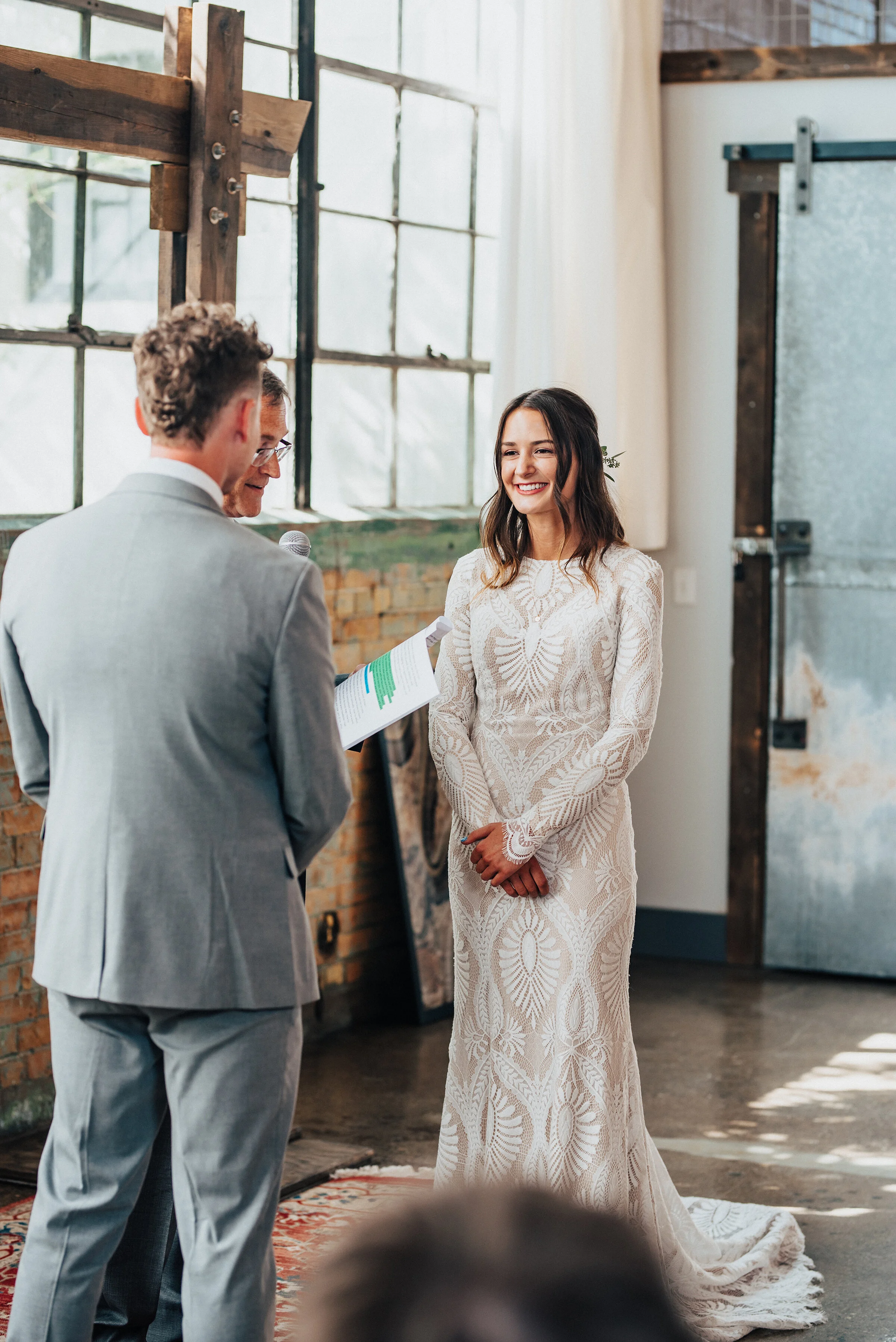  Kristi Alyse Photography photographs bride and groom exchanging their “I Do’s” at the Bright building in Provo, Utah. wedding ceremony, intimate wedding ceremony, bright building provo utah, industrial wedding venue, simplistic wooden wedding arch, 