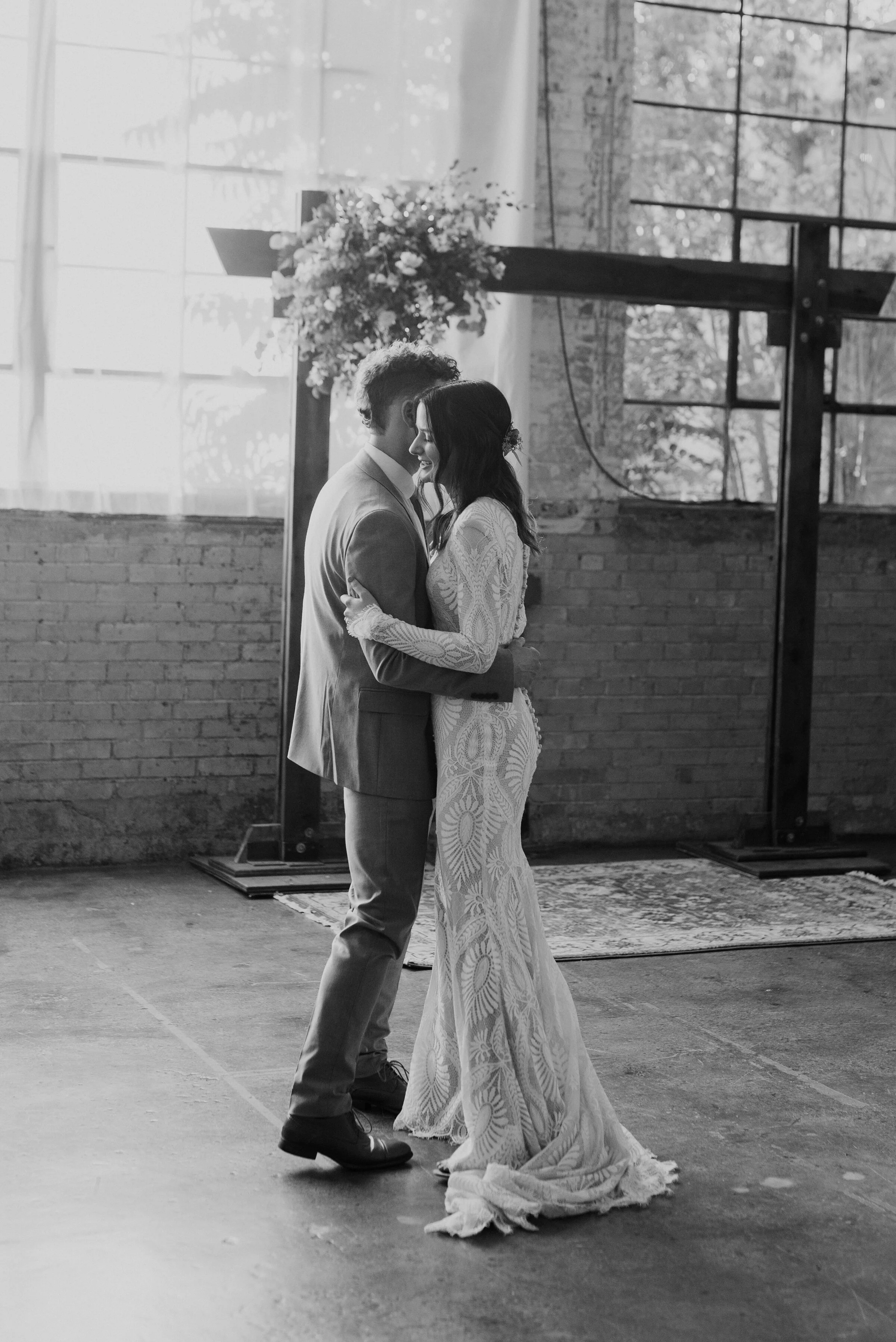 With light beaming through industrial-sized windows and beneath their modern wedding arch, this couple photographed by Kristi Alyse Photography, in Provo, Utah twirls to their first dance at their wedding reception. long sleeved fitted bohemian styl