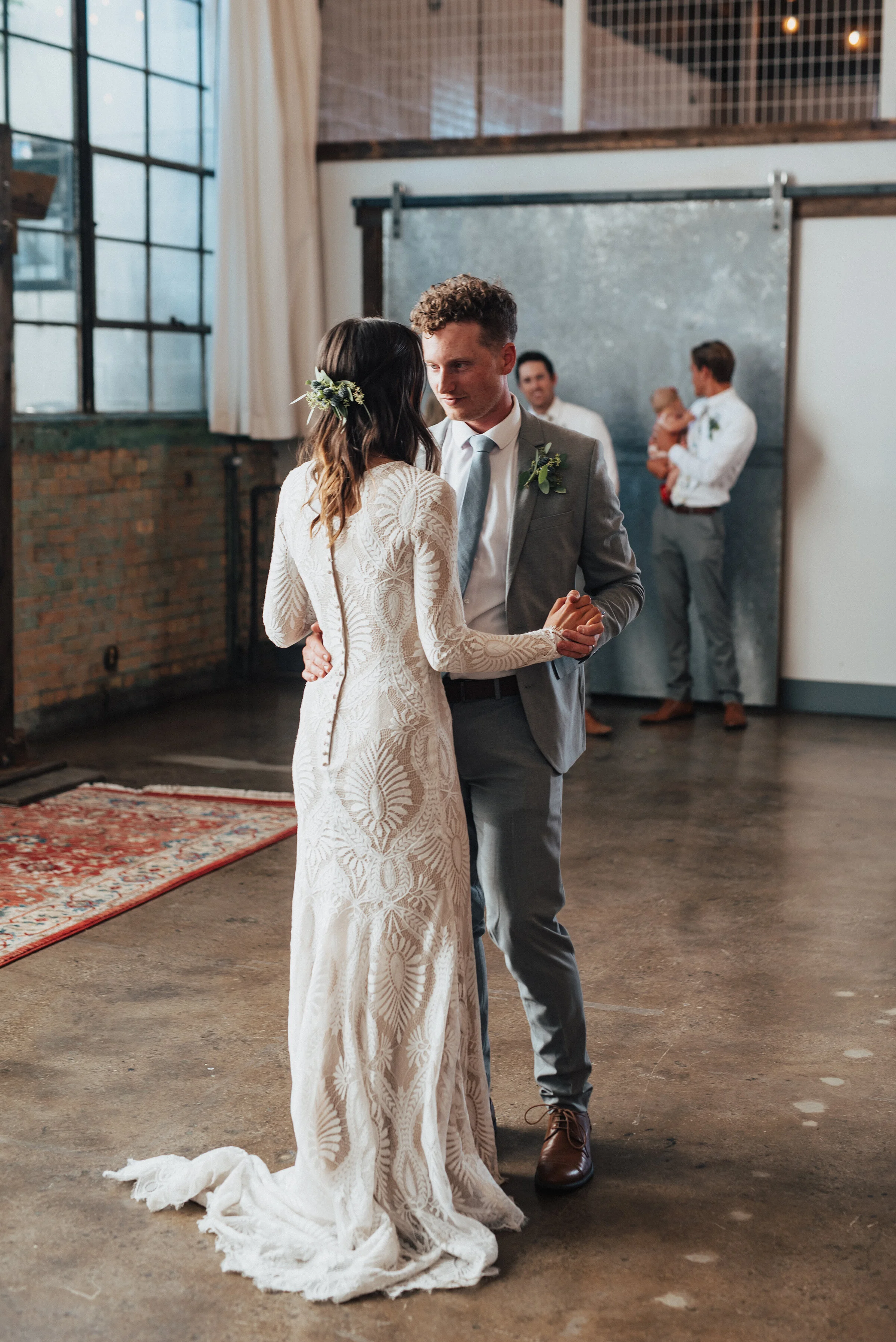  The married couple’s first dance - Kristi Alyse Photography captures newlyweds slow dancing at their bohemian themed reception at the Bright Building in Provo, Utah. buttoned back bohemian dress, modest bohemian wedding dress, long sleeve lace bohem