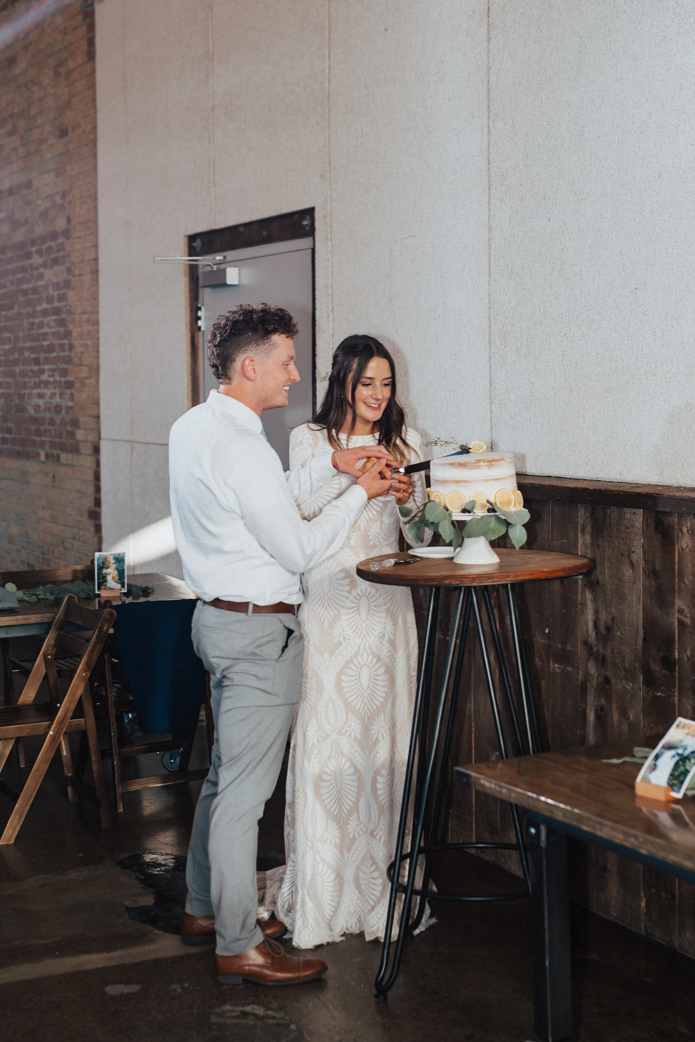  Kristi Alyse Photography captures energetic reception moments of bride and groom cutting their crumb coated wedding cake at the Bright Building in Provo, Utah. cake smashing, wedding cake cutting, preserving wedding cake, professional provo utah wed