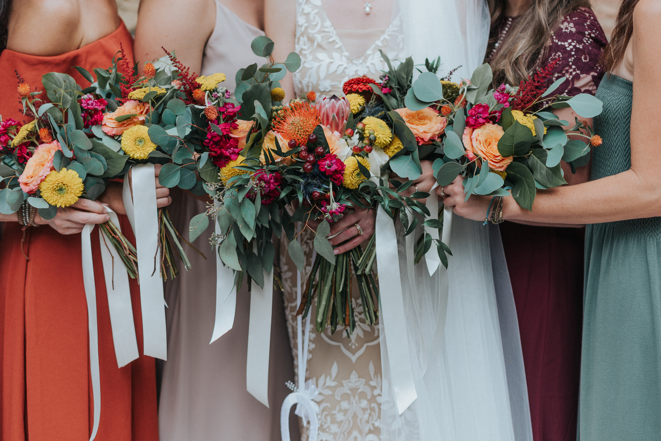 Gorgeous bridal bouquets for bride and bridesmaids with red and yellow and orange for a boho wedding in Northern Utah by Kristi Alyse Photography. wedding flower ideas floral bouquets with berries red yellow orange colors for wedding matching bouque…