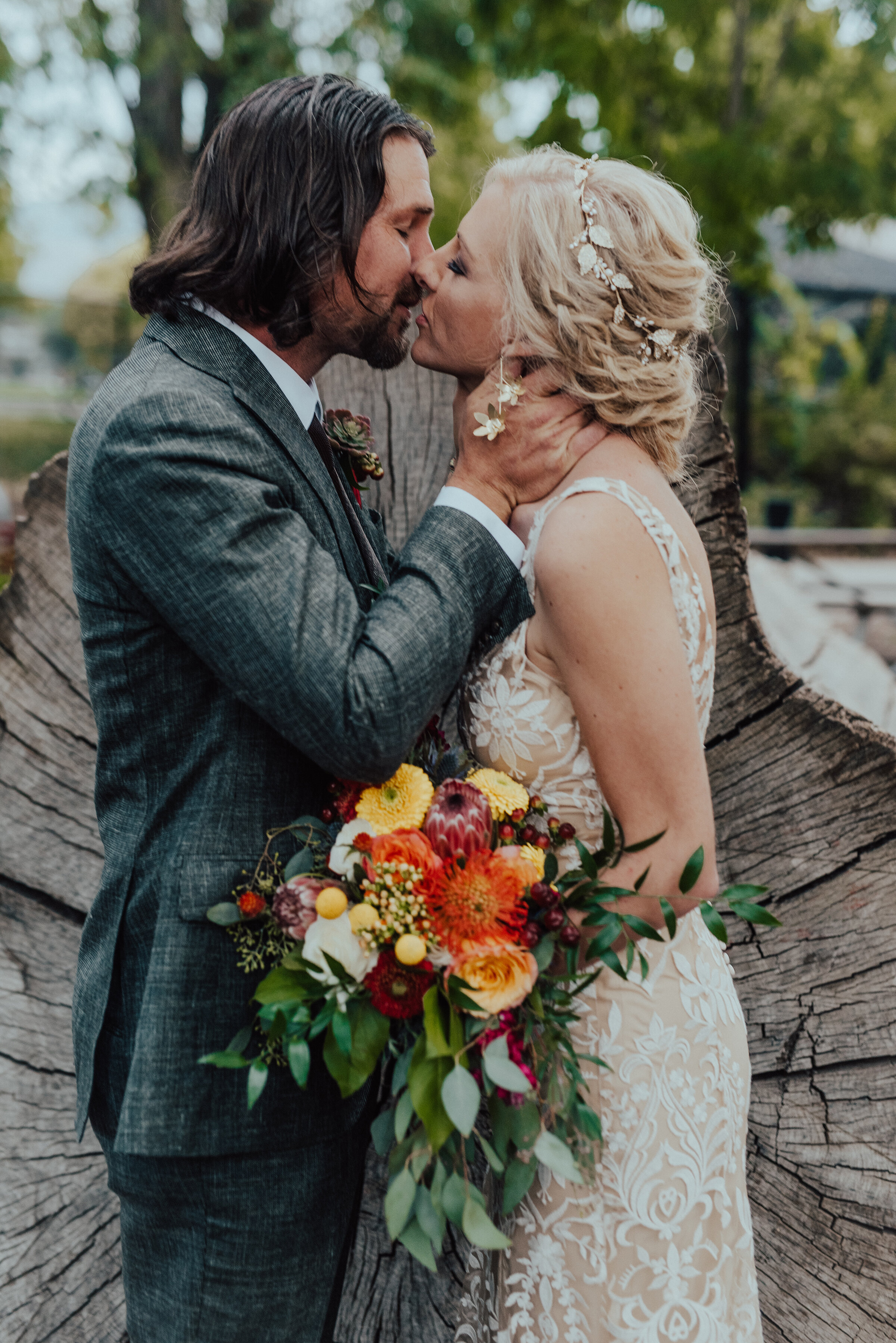  Beautiful couple holding bridal bouquet with yellow and red and orange colors in Salt Lake City, Utah by Kristi Alyse Photography. bridal bouquet ideas for wedding boho wedding flowers red orange yellow wedding colors floral ideas dark gray suit for