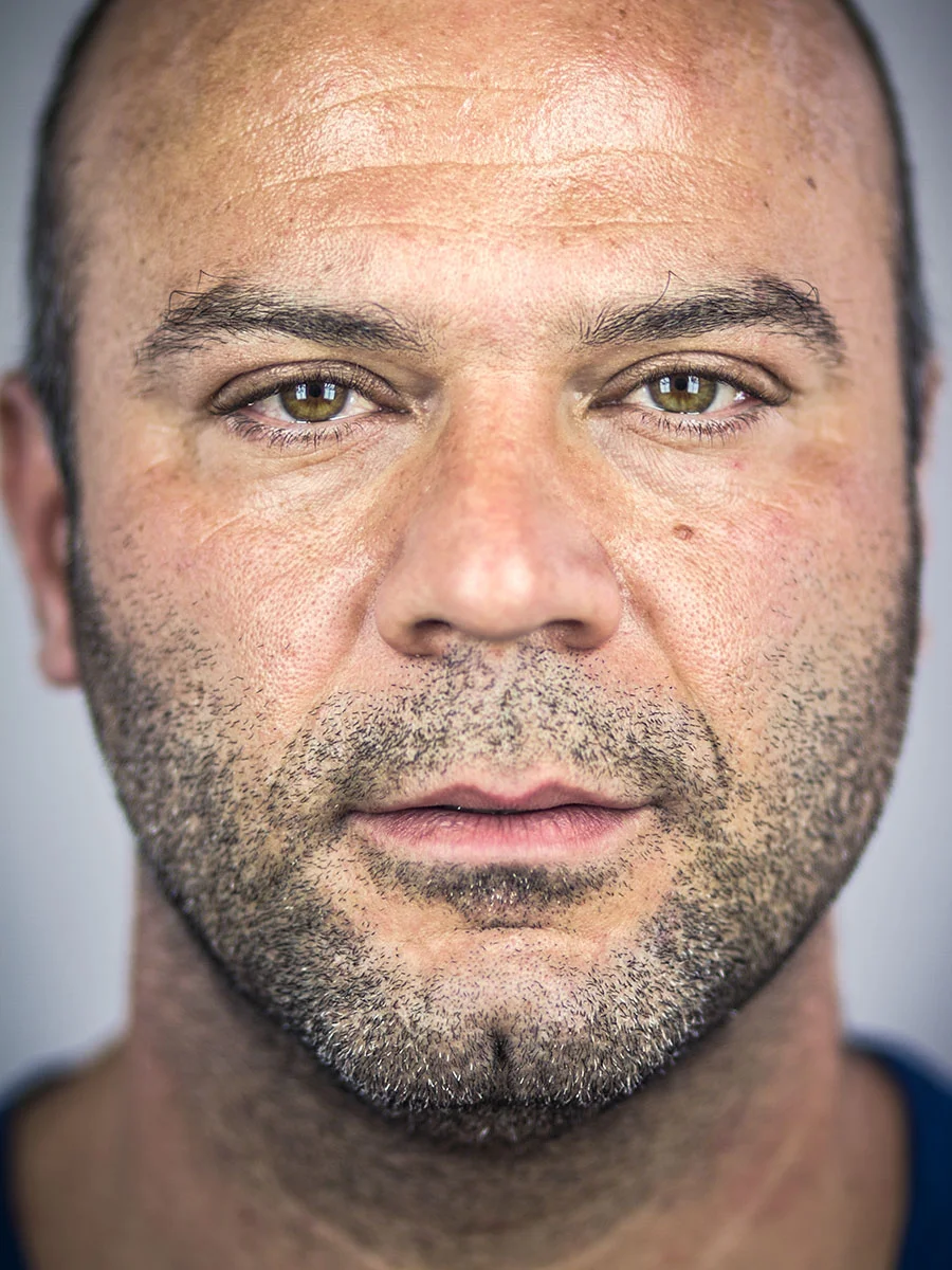 This series of Raw Portraits (Mugs) was created to show the raw beauty of humans. As people were coming in for headshots, I asked them to sit in front of the camera without having any makeup applied, without their hair being done. Then with simple post processing the texture was brought out and skin was slightly desaturated.