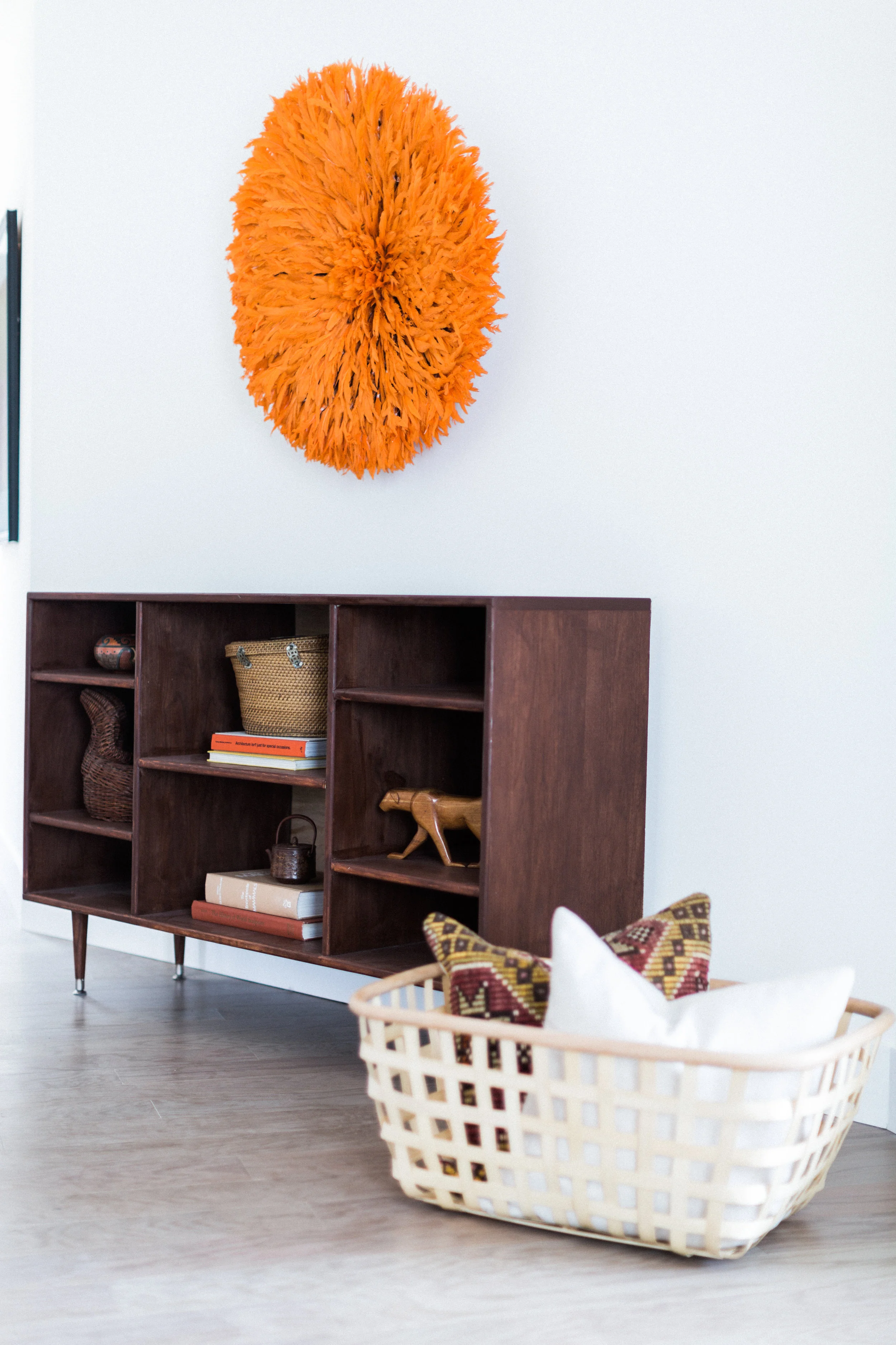 At the entry, this bookcase from LA's Moti Roma holds treasures. And nothing says welcome like a Cameroonian juju feather headdress in shocking orange. We even love IKEA's Viktigt basket to hold more kilim-y goodness.