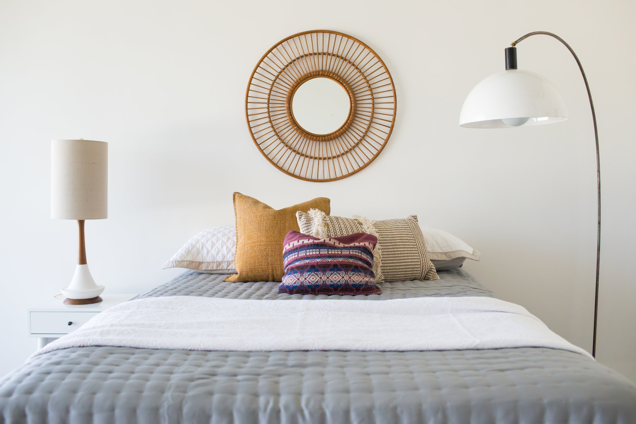 In another bedroom, a vintage arc lamp, embroidered pillow and Mid Century lamp.