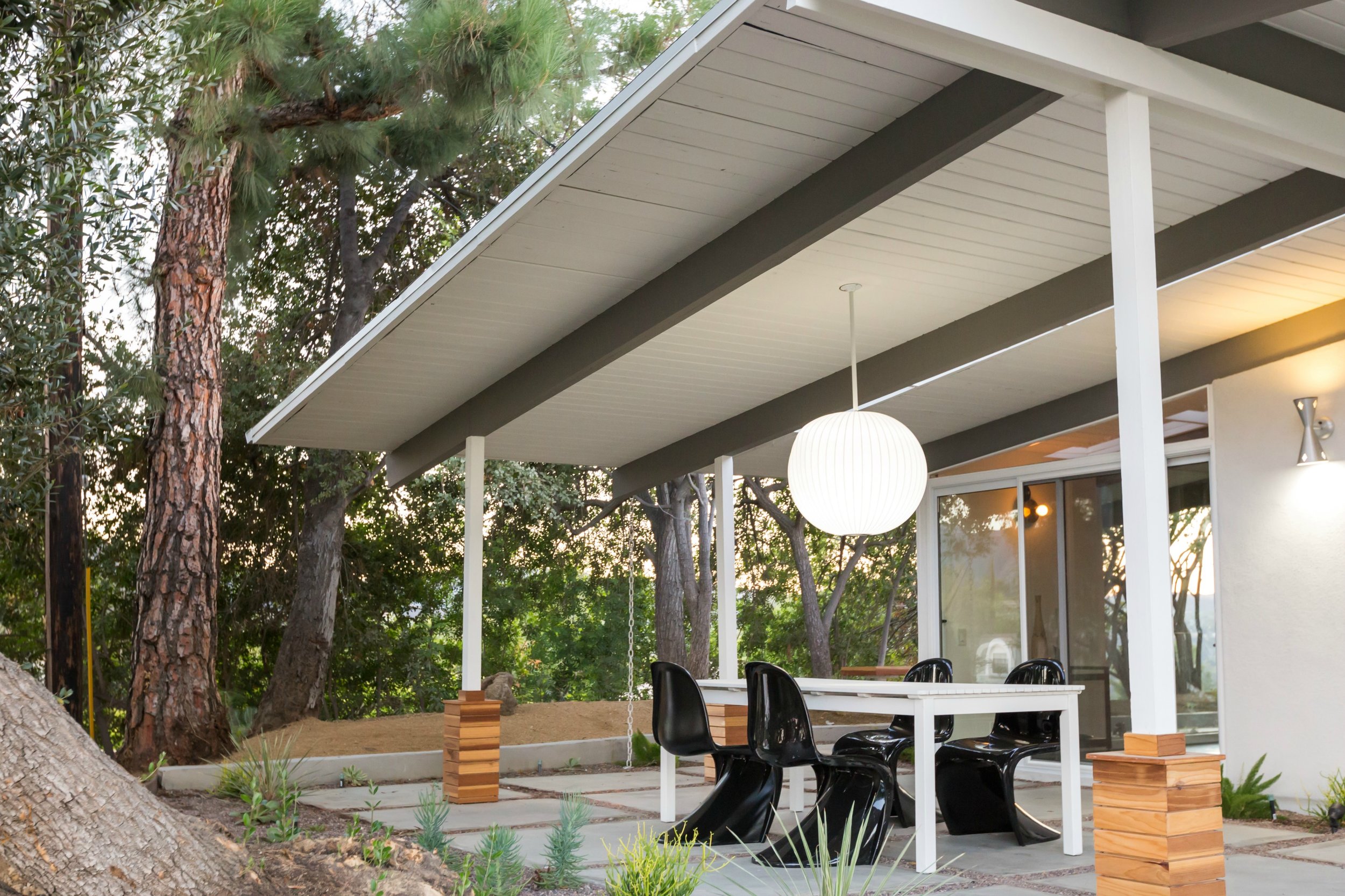 To play up the inherent drama in the outside patio's pendant light, we added the dark and light contrast of black Panton chairs around a white picnic table.