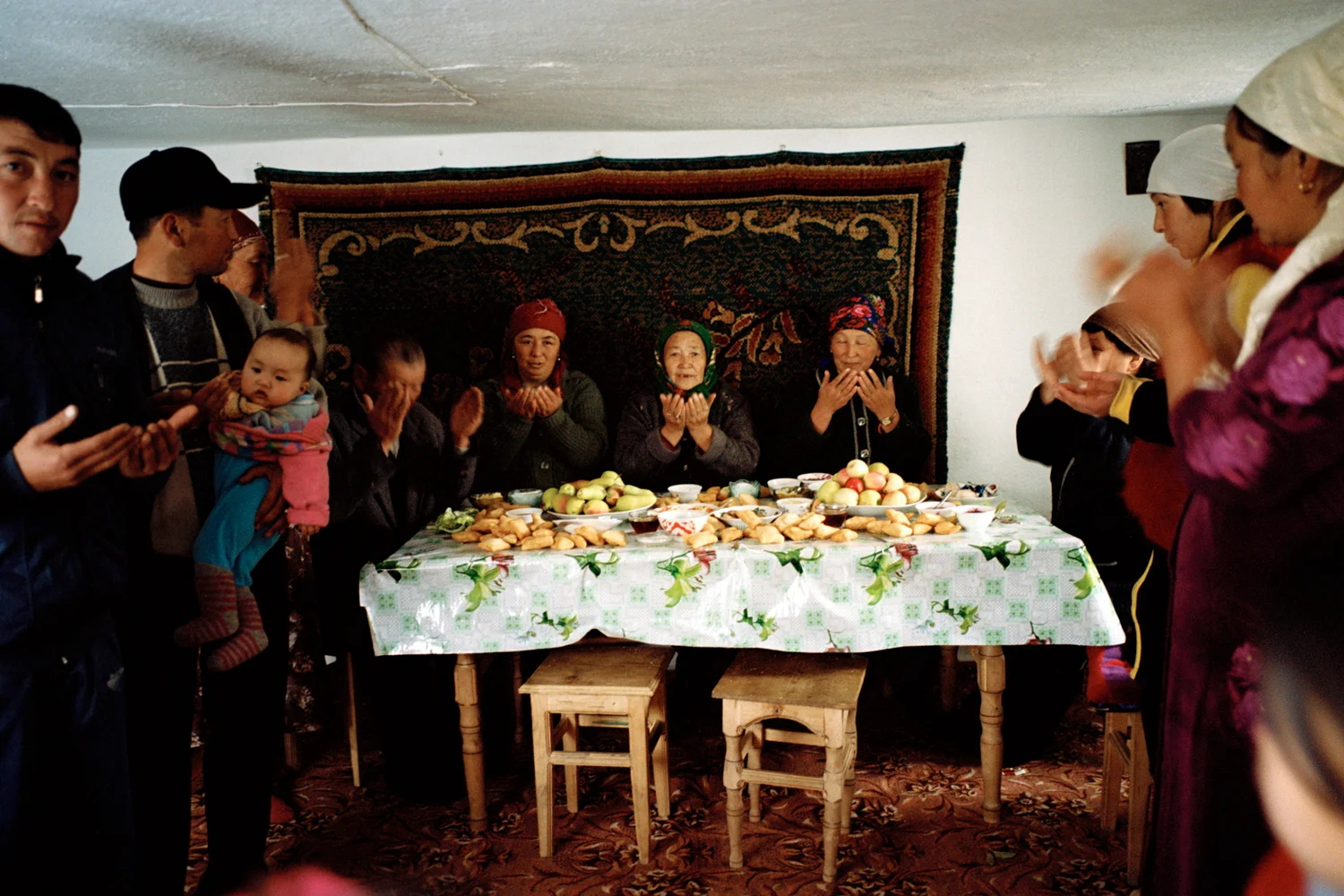 Guests give thanks for a wedding feast at a house where a girl was kidnapped three days previously. After a wedding the family of the groom open their doors to friends and neighbours to visit and admire the new daughter-in-law. An animal is slaughtered and celebrating can last up to a month. Issyk-Kul Oblast, Kyrgyzstan.