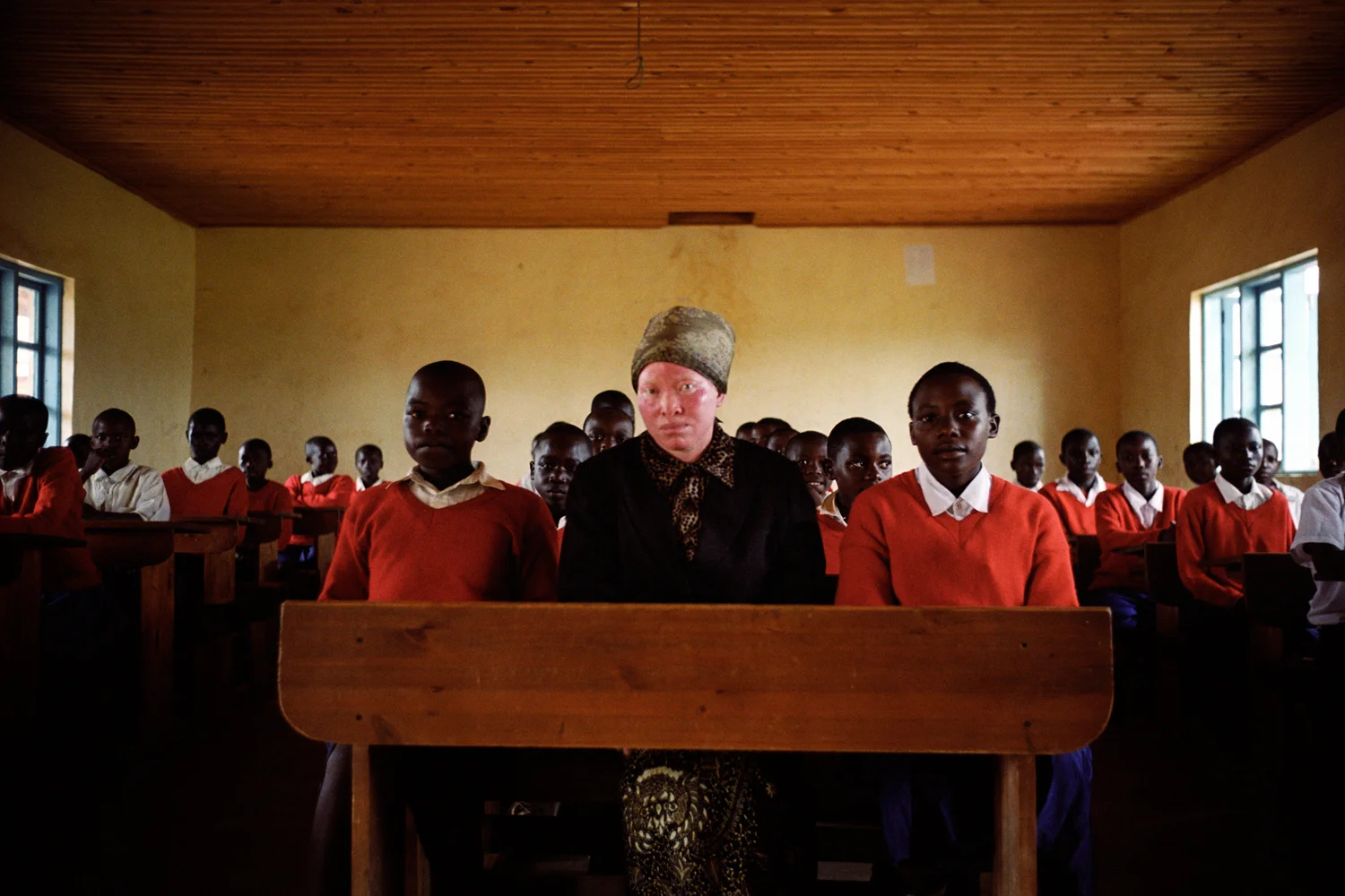 Martha Hahle with the class she teaches. As a person with albinism she is lucky to have a job and one that is indoors, out of the sun. Ingrained prejudice means that even people with albinism who are educated find it hard to get employment. Ihefu Primary School, Mufindi District, Tanzania. 