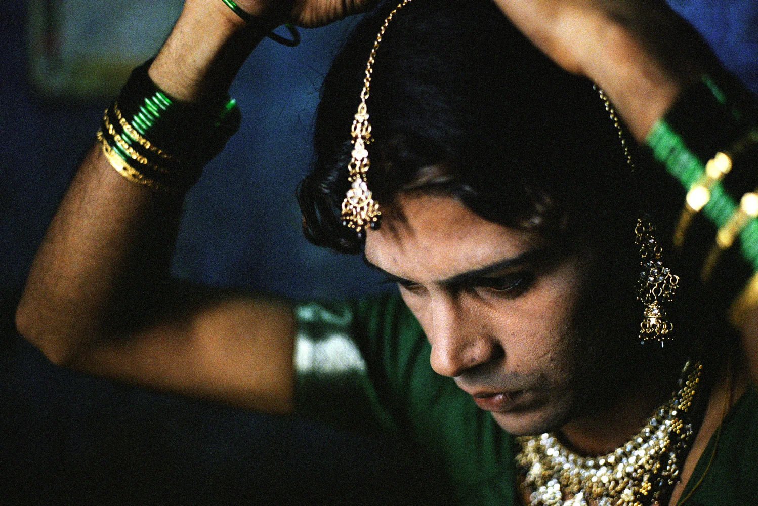 Raju dresses to go out collecting alms in the name of Yellamma. The green bangles and mangal sutra (black and gold necklace and headdress) are the traditional adornments of married women in the Hindu culture.