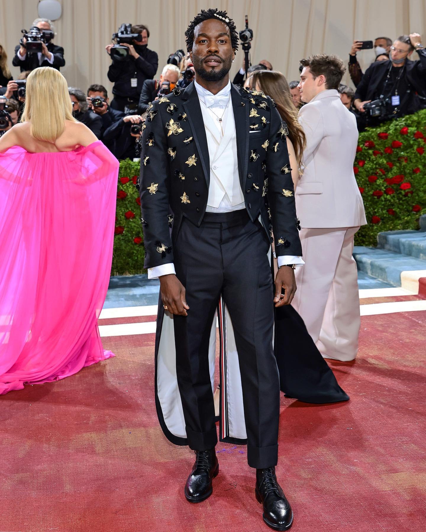 Yahya Abdul-Mateen II is an elongated floor length tailcoat in 3-ply mohair with orchids &amp; laurel leaves embroidery in gold bullion, tuxedo trousers in mohair &amp; wing collar shirt.