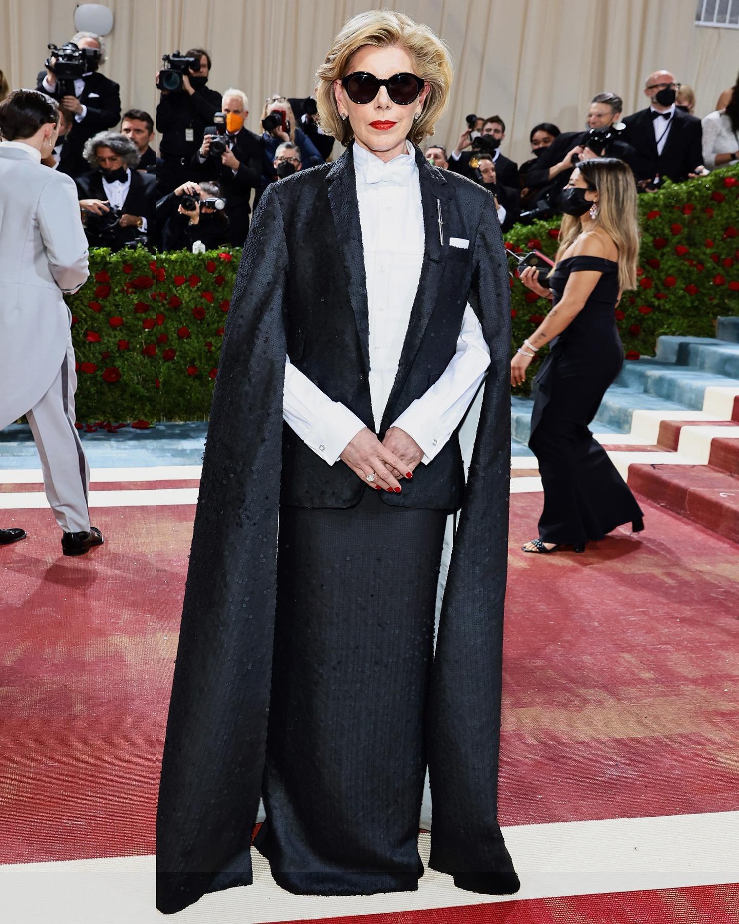Christine Baranski wears a matte black sequin ticket pocket jacket with cape-back.