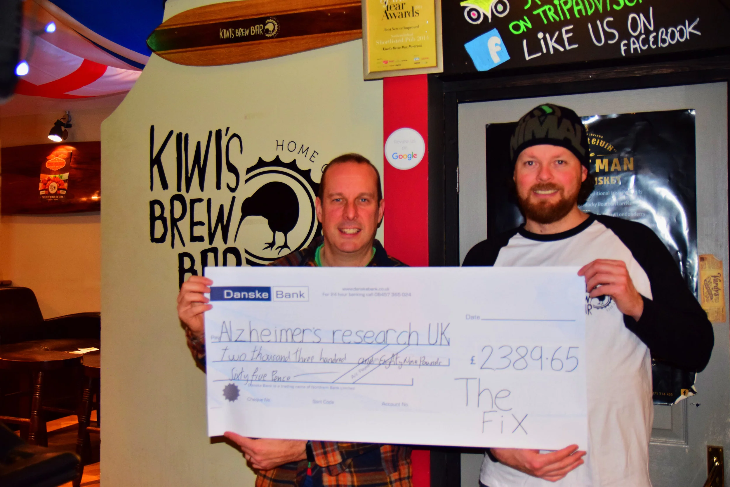 Job done: Jonny Lennox (left), frontman of The Fix, and Kris Charteris, owner of Kiwi’s Brew Bar, display a cheque for Alzheimer’s Research UK following the band’s 25-year charity reunion night