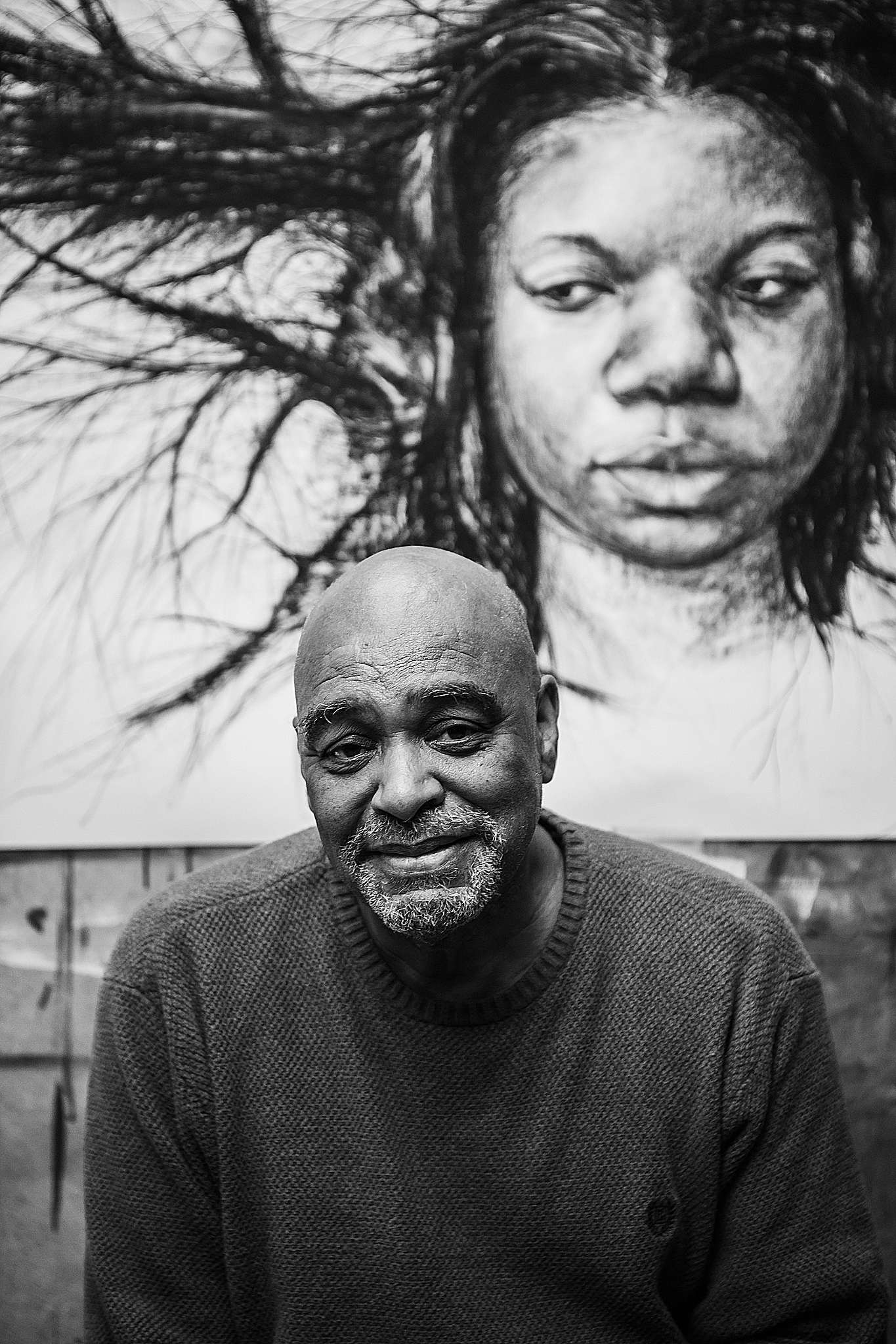 black and white photo of man in front of mural