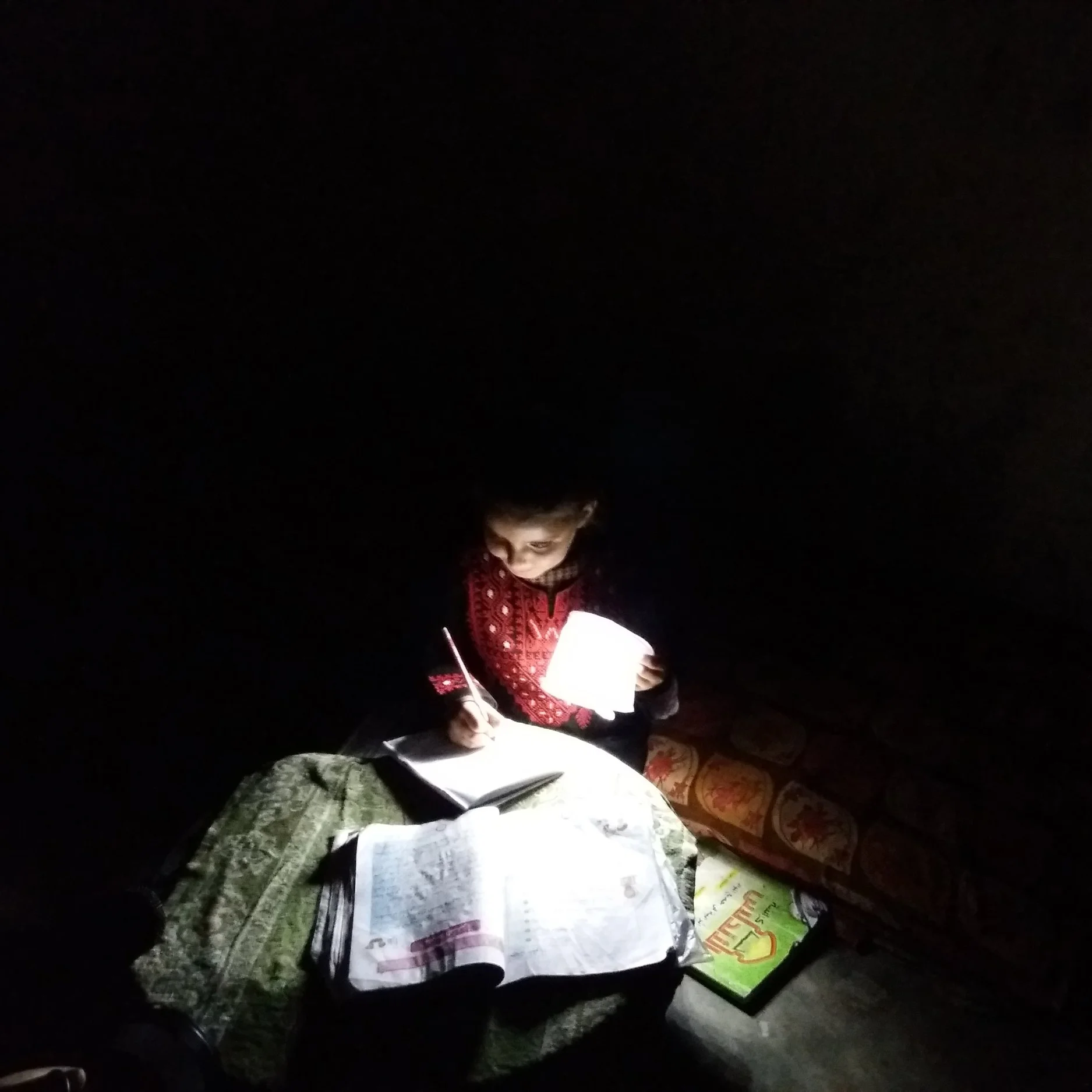 Maram reading with help from one of the solar lights donated by Rebuilding Alliance