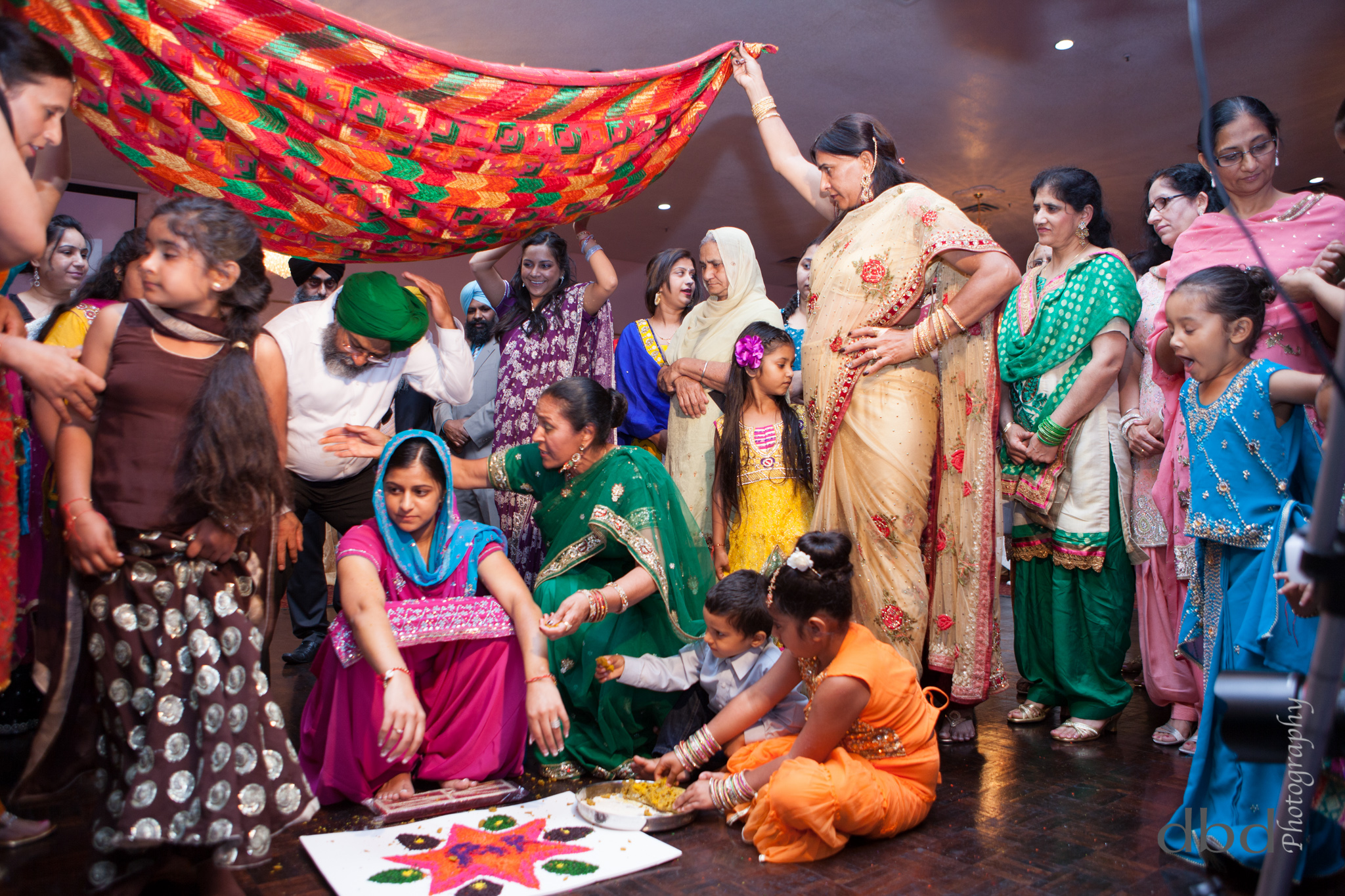  The&nbsp; dupatta &nbsp;scarf is held above the girls head by four family members 