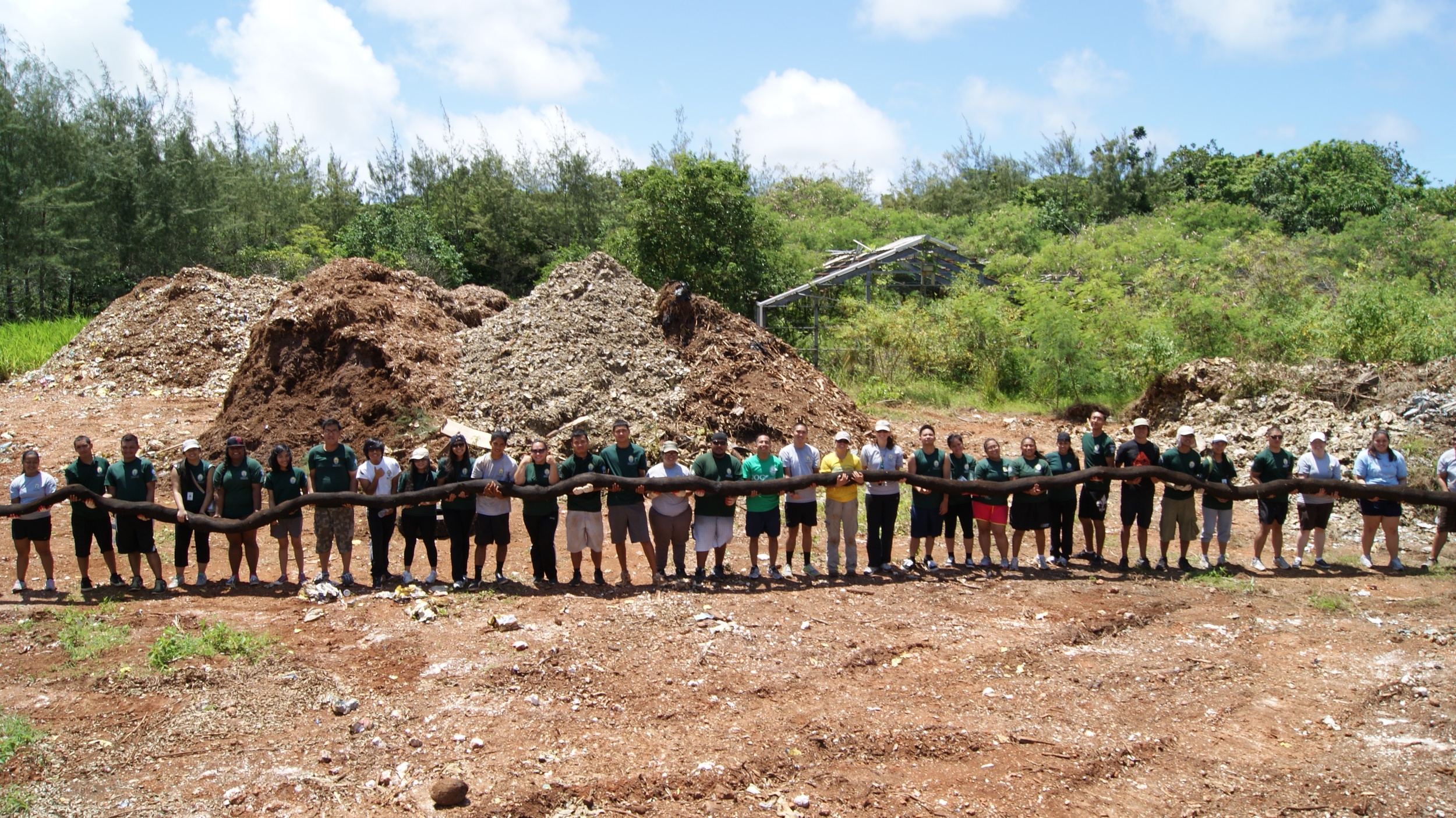 AmeirCorps University of Guam Members standing with sediment filter socks, which are mesh stockings filled with mulch that are installed in eroding hillsides to decrease erosion and promote revegetation.