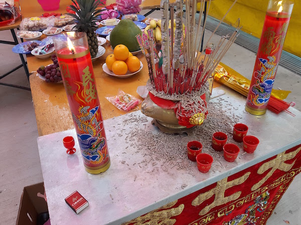 A joss table with small cups of wine and tea. Three sticks of incense must be lit when making prayers. 