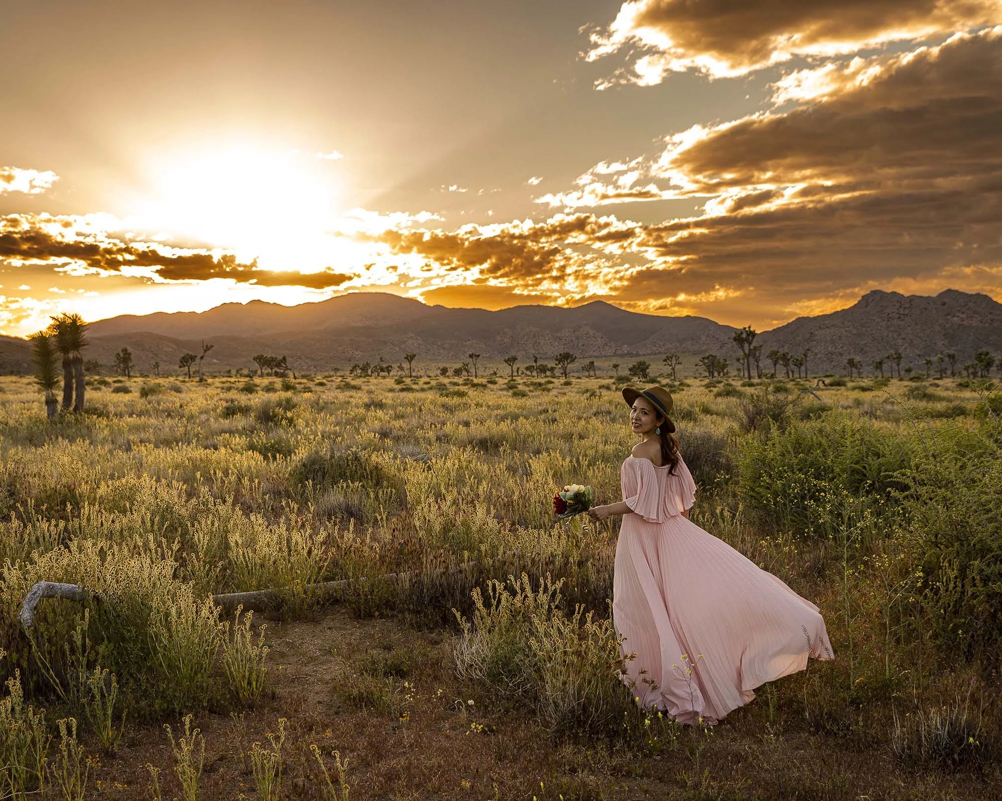 ジョシュアツリー国立公園での前撮りで風になびくピンクのドレスを着た奥さま