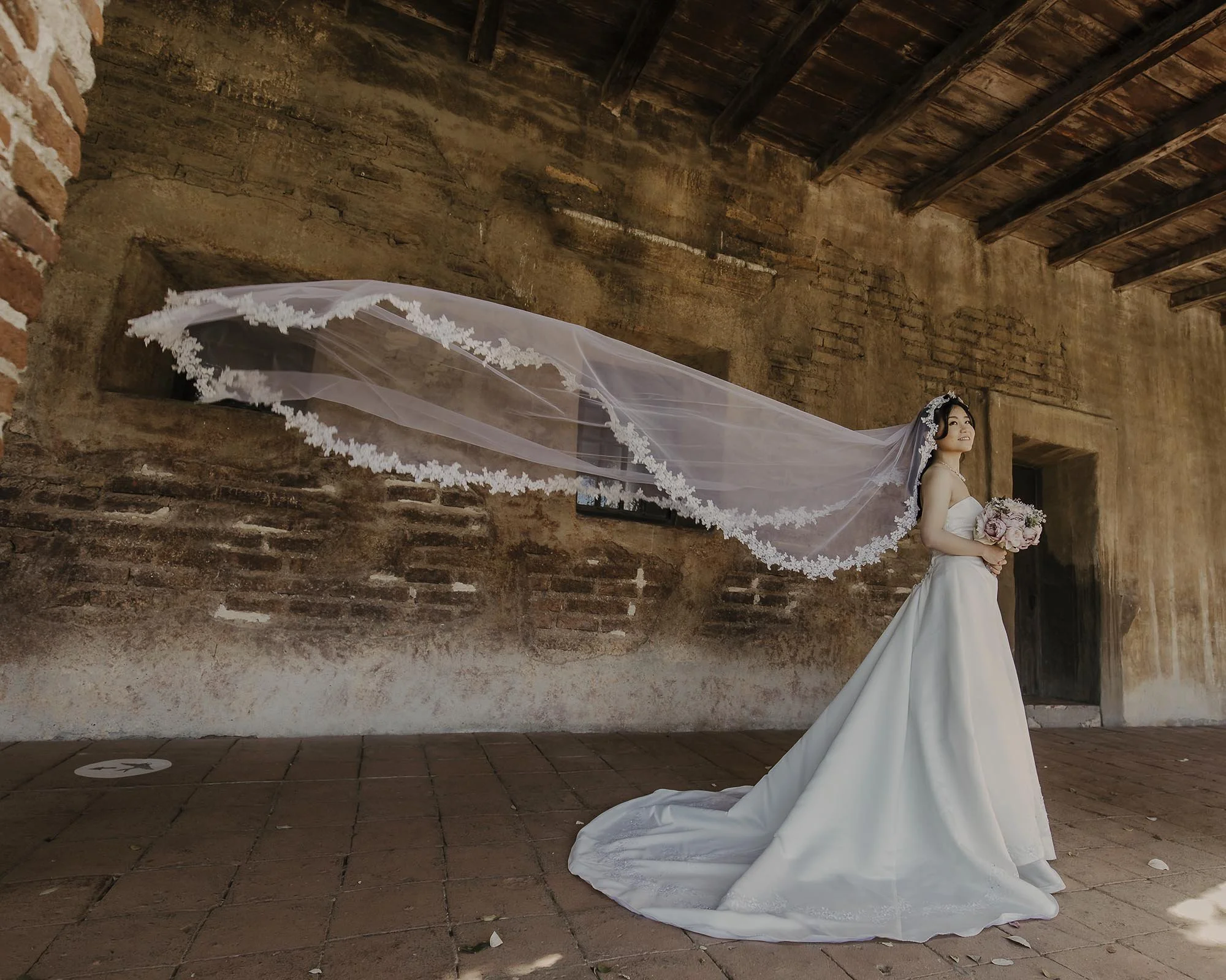 ミッション・サンファンキャピストラーノでのウェディング撮影で風になびくベールが美しい奥さま