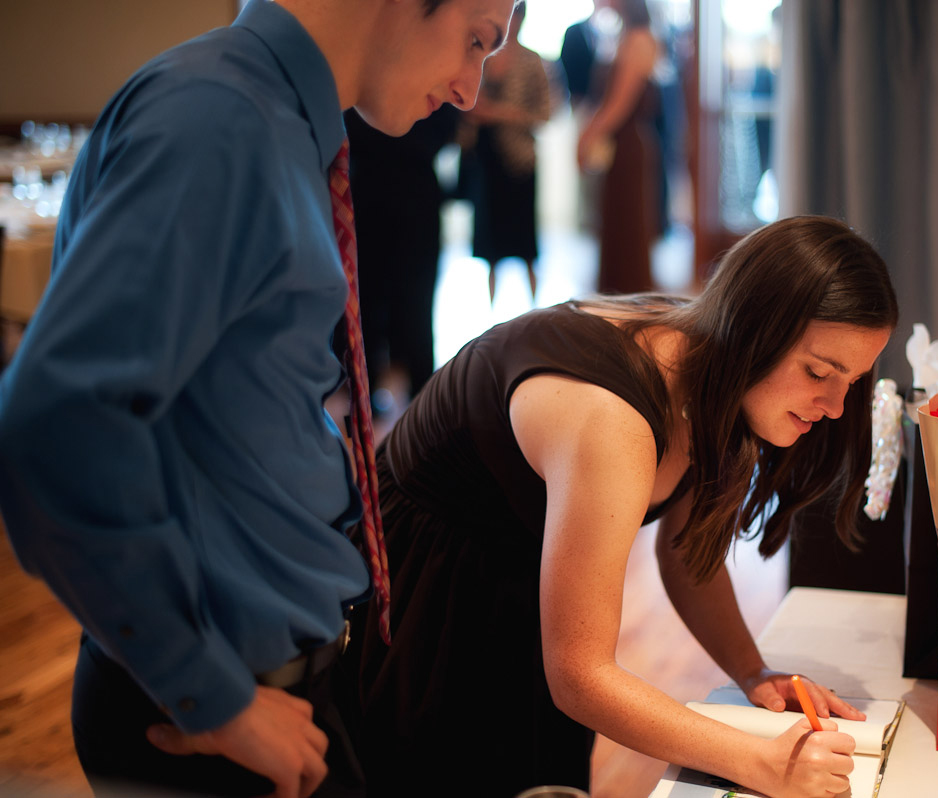 Wedding guests writing well-wishes in Emma and Jake's guest book