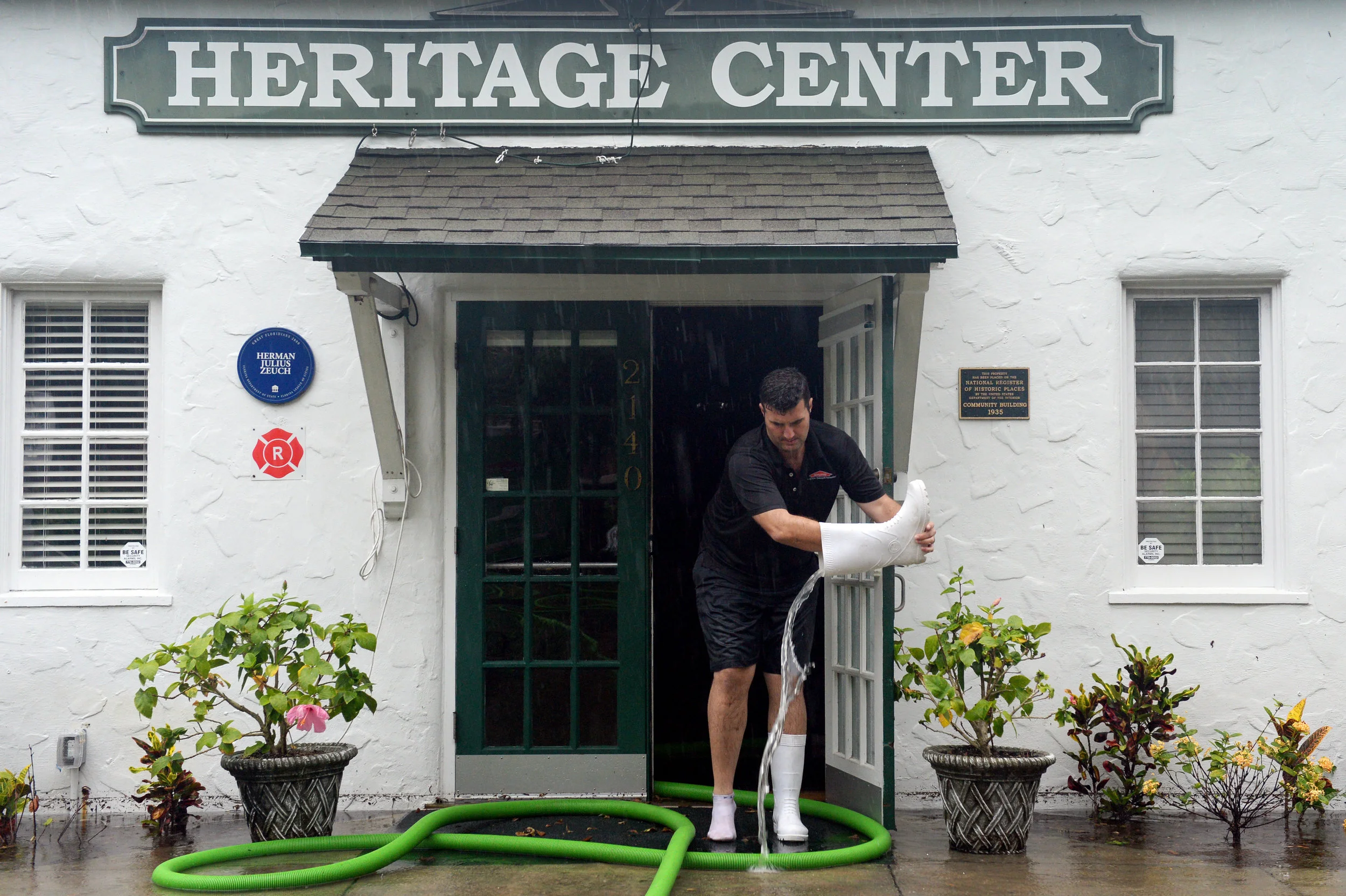  Nico Strydom, with Servpro of Vero Beach, pours water out of his boot after wading through knee-high flooding Tuesday around the Heritage Center in downtown Vero Beach. The interior of the center began taking water after day-long thunderstorms dropp