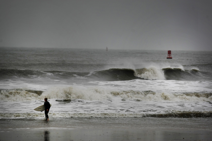 Todd Jarvis, of Virginia Beach, emerges front the surf after he determined the currents were too hard to surf as Hurricane Sandy pounded the Virginia coastline.