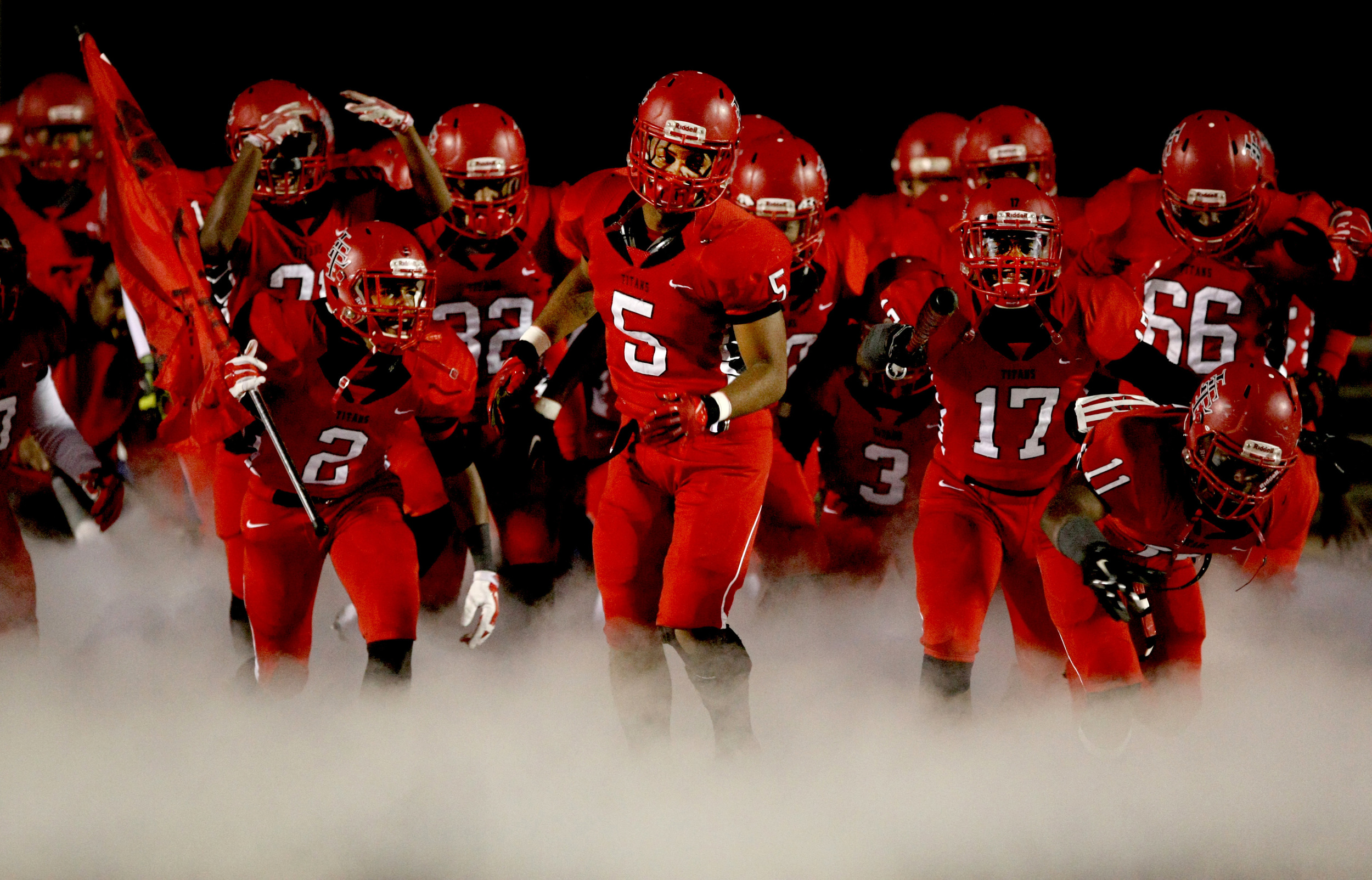 Lake Taylor's Marquis Poole, center, leads the Titans onto the filed prior to the start of their game against Monacan.