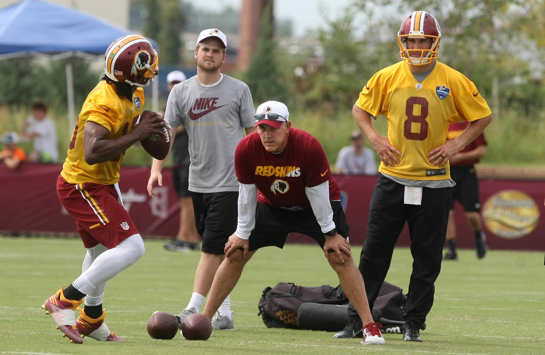 Washington Redskins quarterbacks coach Matt Cavanaugh, center, works with quarterback Robert Griffin III, left, during the team's NFL football training camp in Richmond, Va., Thursday, July 30, 2015. (AP Photo/Jason Hirschfeld)