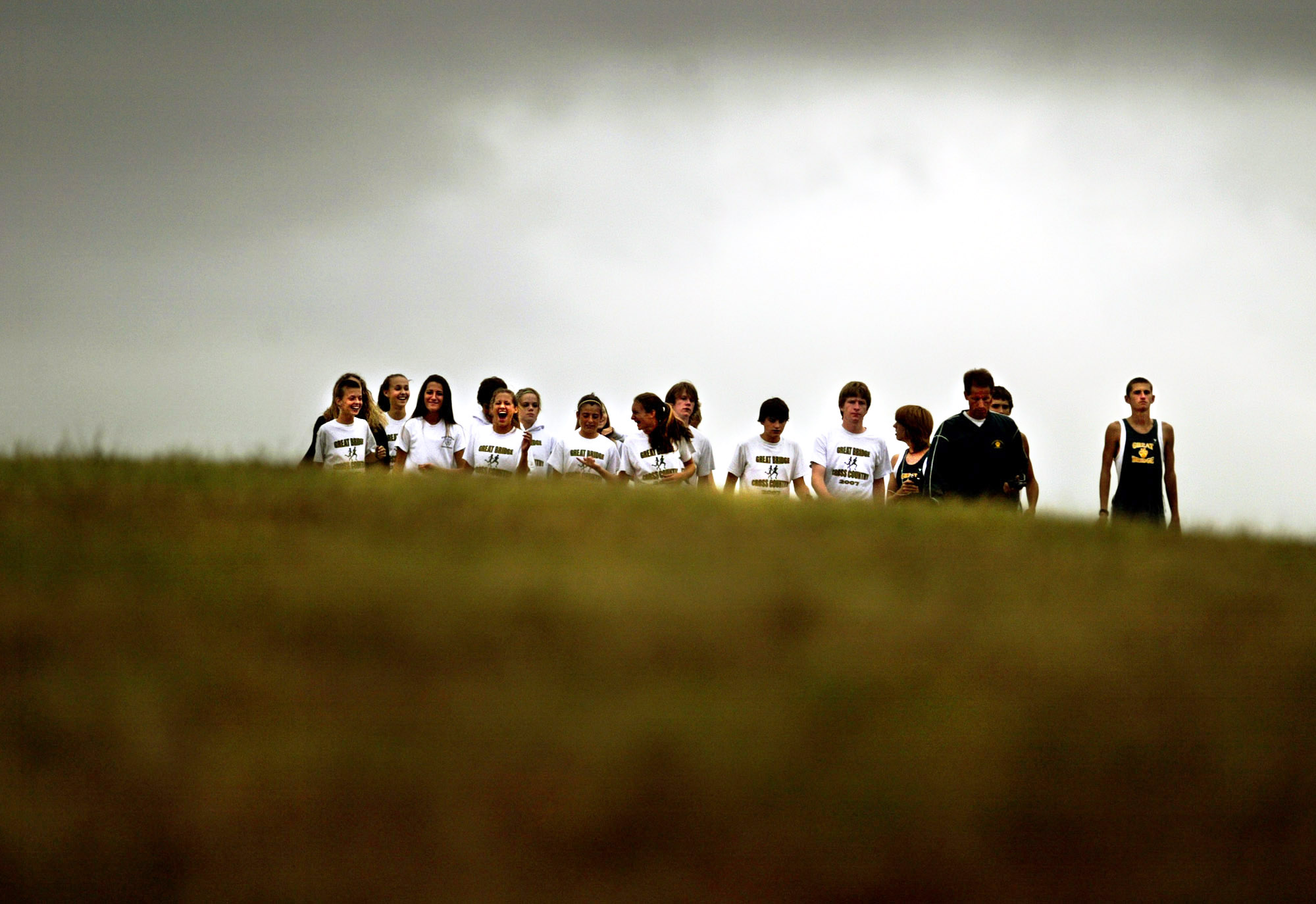 The Great Bridge Cross Country team emerges from the top of a hill before the start of a meet.