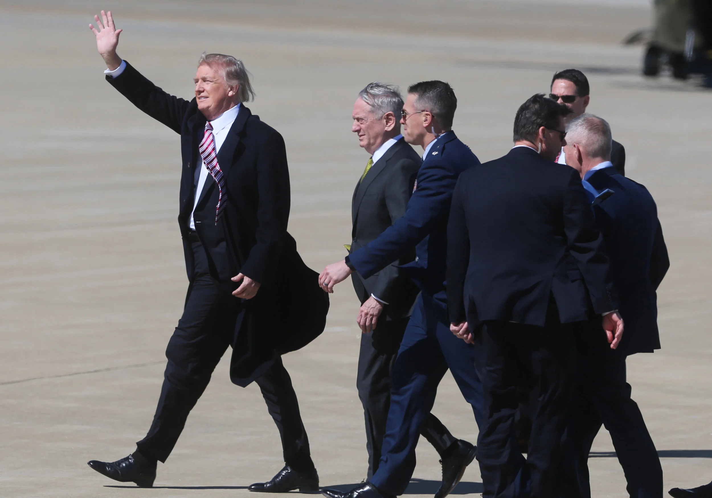 President Donald Trump fights through high winds and waves to a small crowd of supporters upon his arrival alongside Secretary of Defense Gen. James Mattis, Thursday, March 2, 2017 at Langley Air Force Base in Hampton, Va.