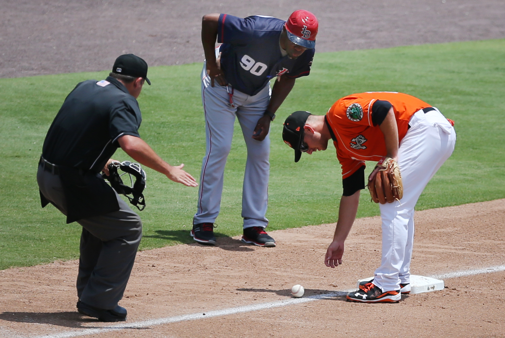 Tides third baseman Chris Johnson, right, home plate umpire Jerry Riggs, left, and Louisville manager Delino Deshields watch as the ball slowly rolls foul during the Tides' 3-1 win, Thursday, June 29, 2017 at Harbor Park in Norfolk. 