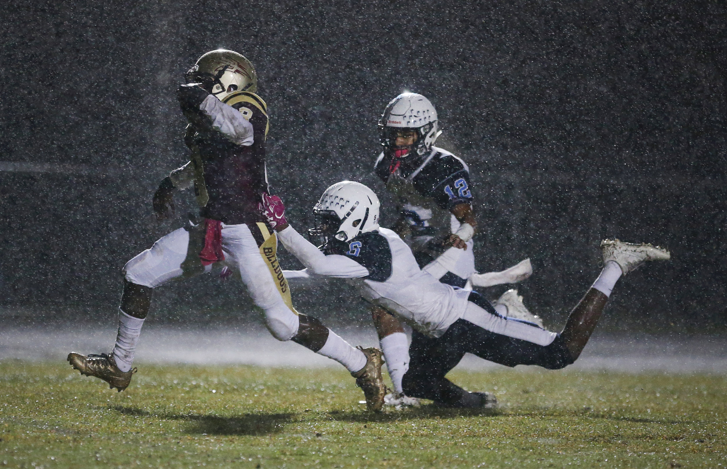 On a rain-soaked night, King's Fork's Darran Butts breaks past Indian River's Demetri Payne, center, and Isaiah Hyman for a first quarter touchdown, Friday, Oct. 13, 2017 at King's Fork High School in Suffolk.
