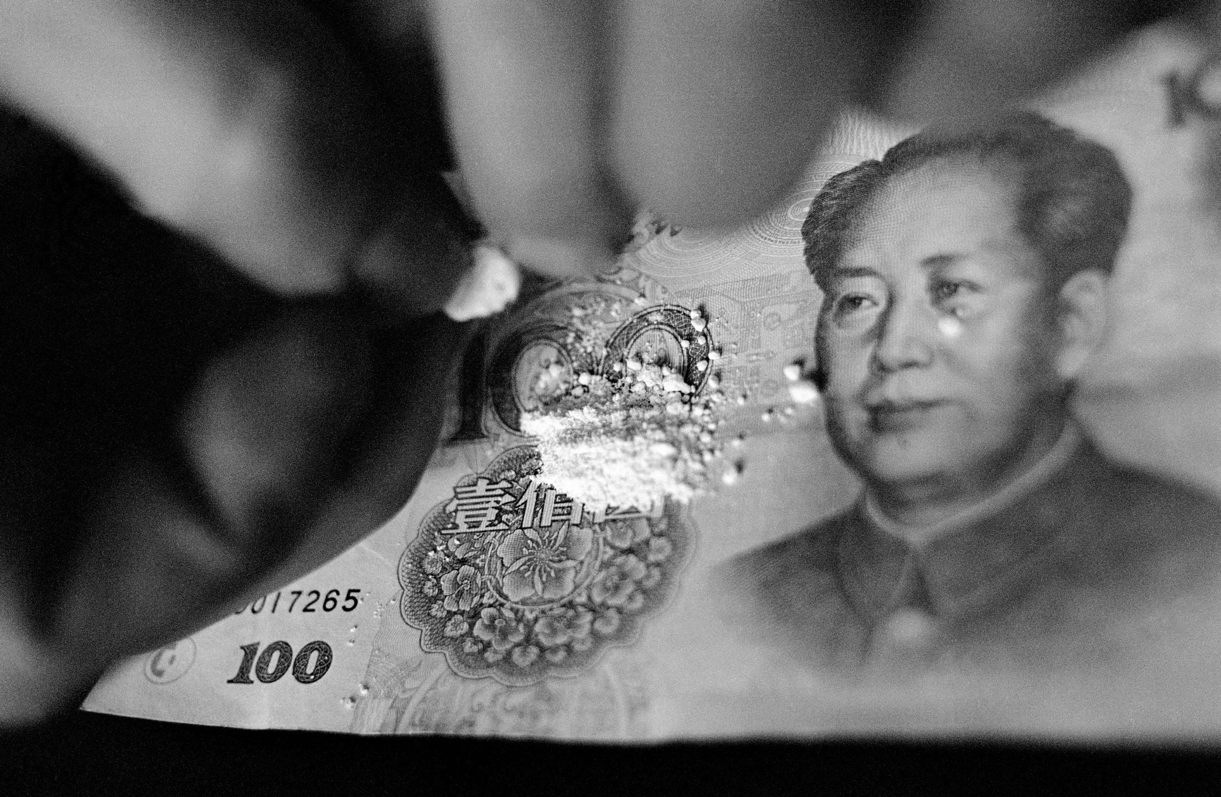 Lanzhou, 2002.  Drug user opens a pod of heroin on a 100-yuan note 