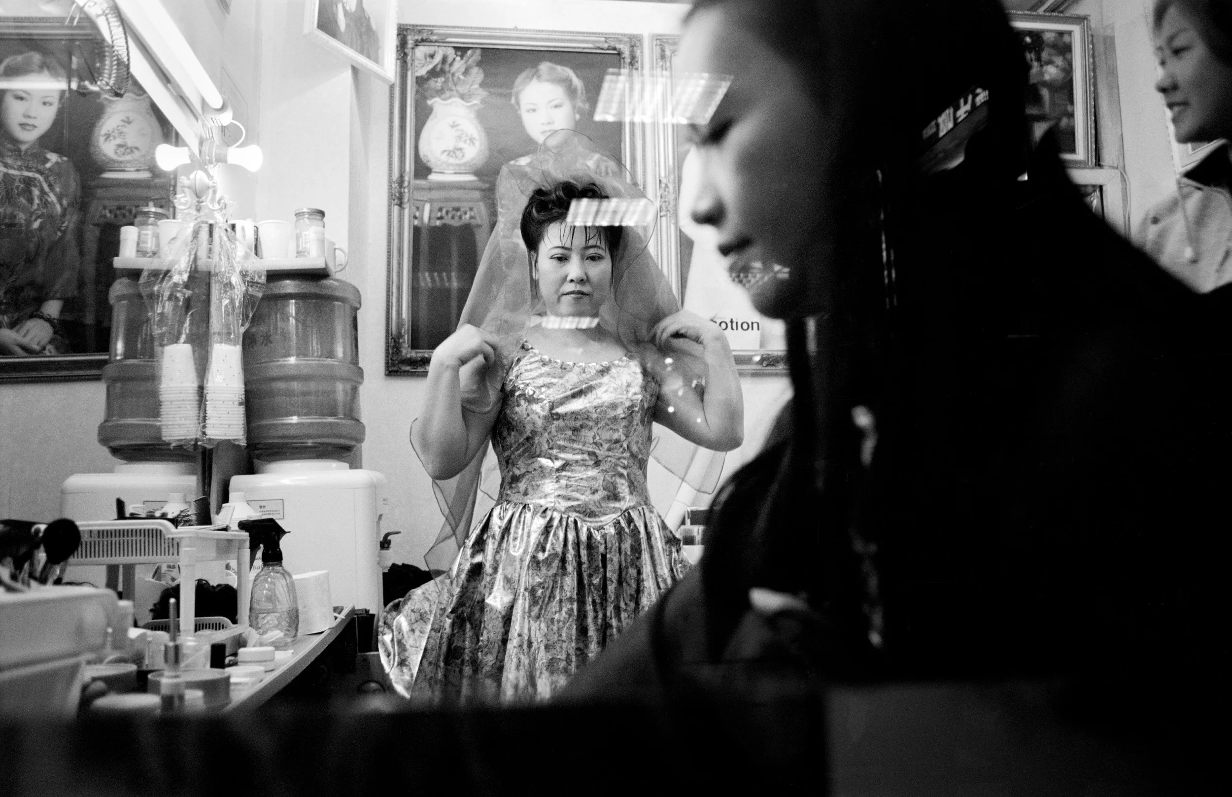  Shenzhen, 1999.  Young married woman tries on a bridal dress at a photography studio, having finally saved enough to get her photos wedding done 