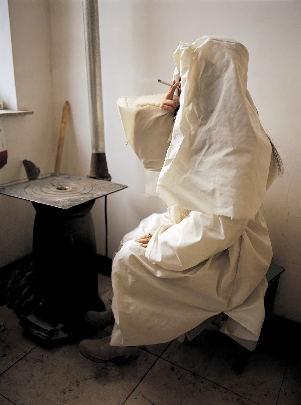  Shanxi, 2005.  A young urban ad executive, dressed in white for her maternal grandmother’s rural village funeral, has a cigarette during a break in the mourning.  Her government official father does not attend for fear of appearing to support ritual