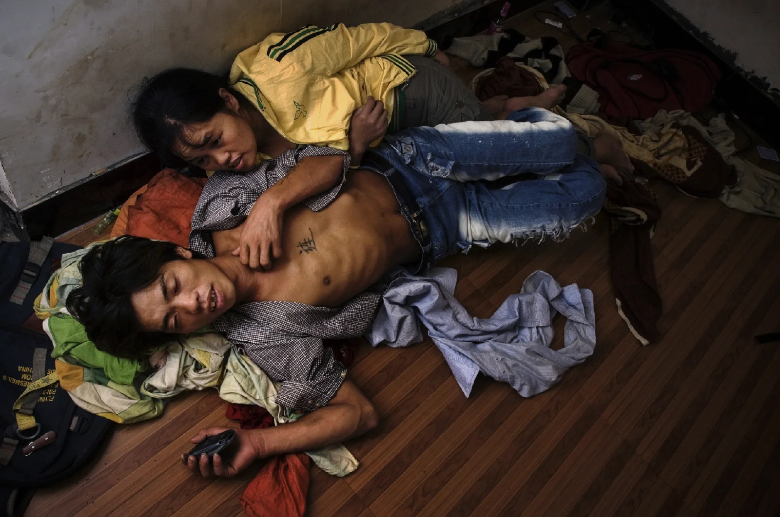 Lishui, 2005.  A construction worker from Hunan Province sleeps on the floor together with his girlfriend who he met in their last stop on the boomtown circuit. They share this tiny unfurnished apartment that costs $20 a month with 4 other guys from