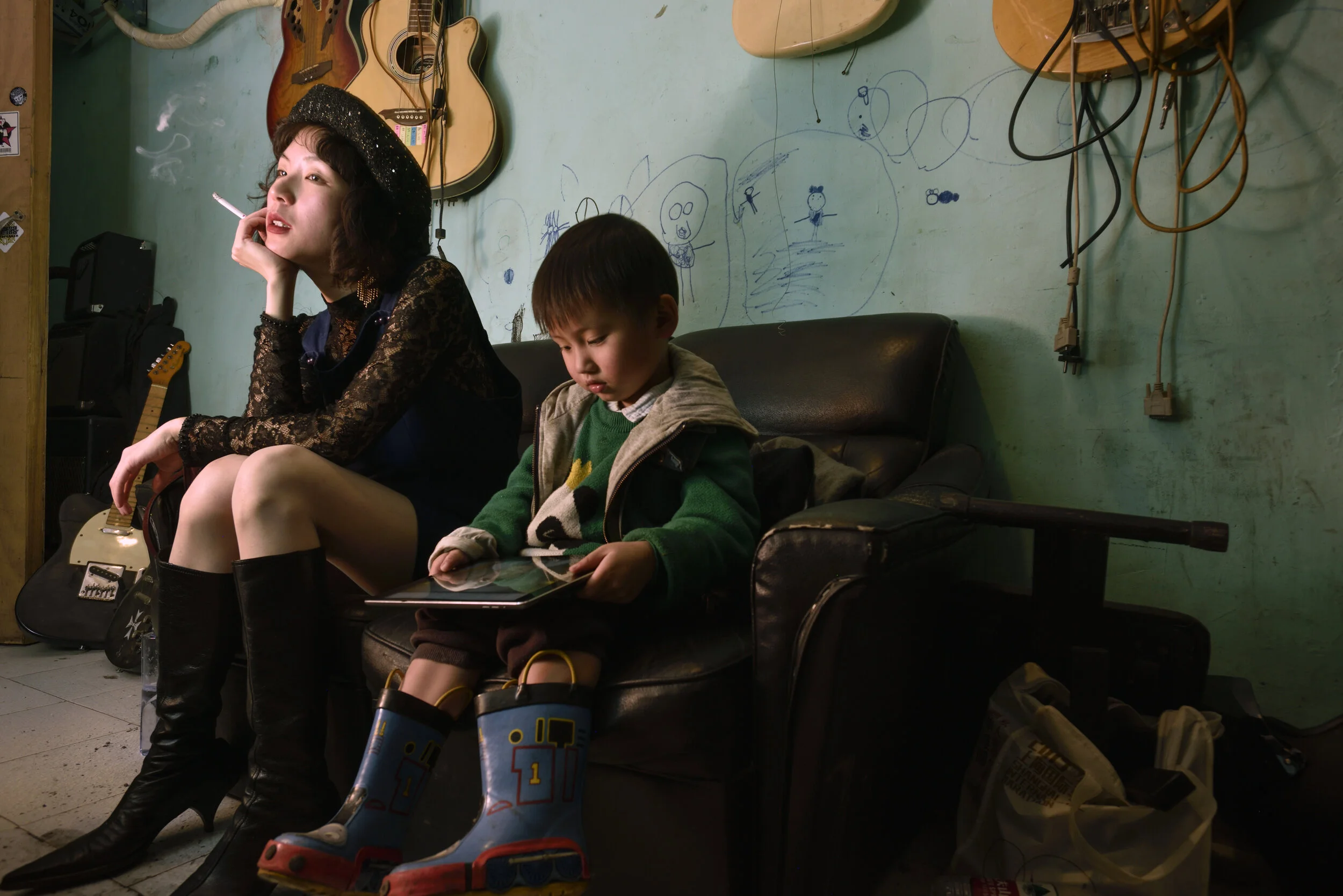 Shanghai, 2018. Design student Liu Mengsi, 23, waits for her boyfriend A Ming at band practice, babysitting his son outside the rehearsal room. Last year they broke up and she is now working in a karaoke bar.   