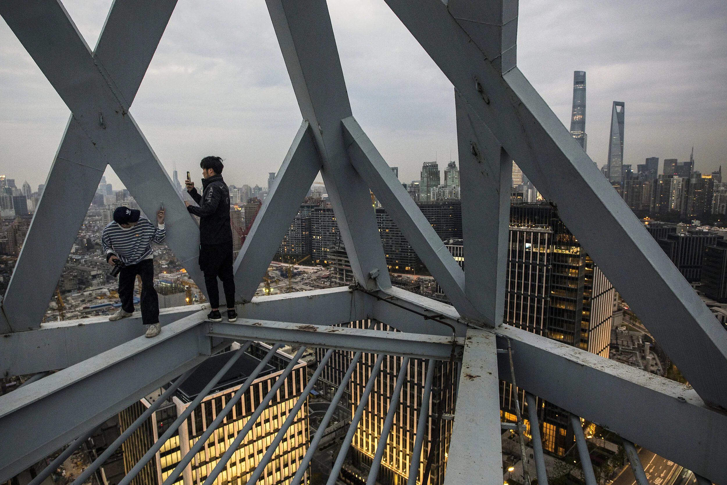  Shanghai, 2019. Young rooftoppers (who are students, materials buyers and insurance agents by day) bypass security guards and pick locks to ascend tall buildings to take photos of and against the cityscape from on high. They post their best pictures