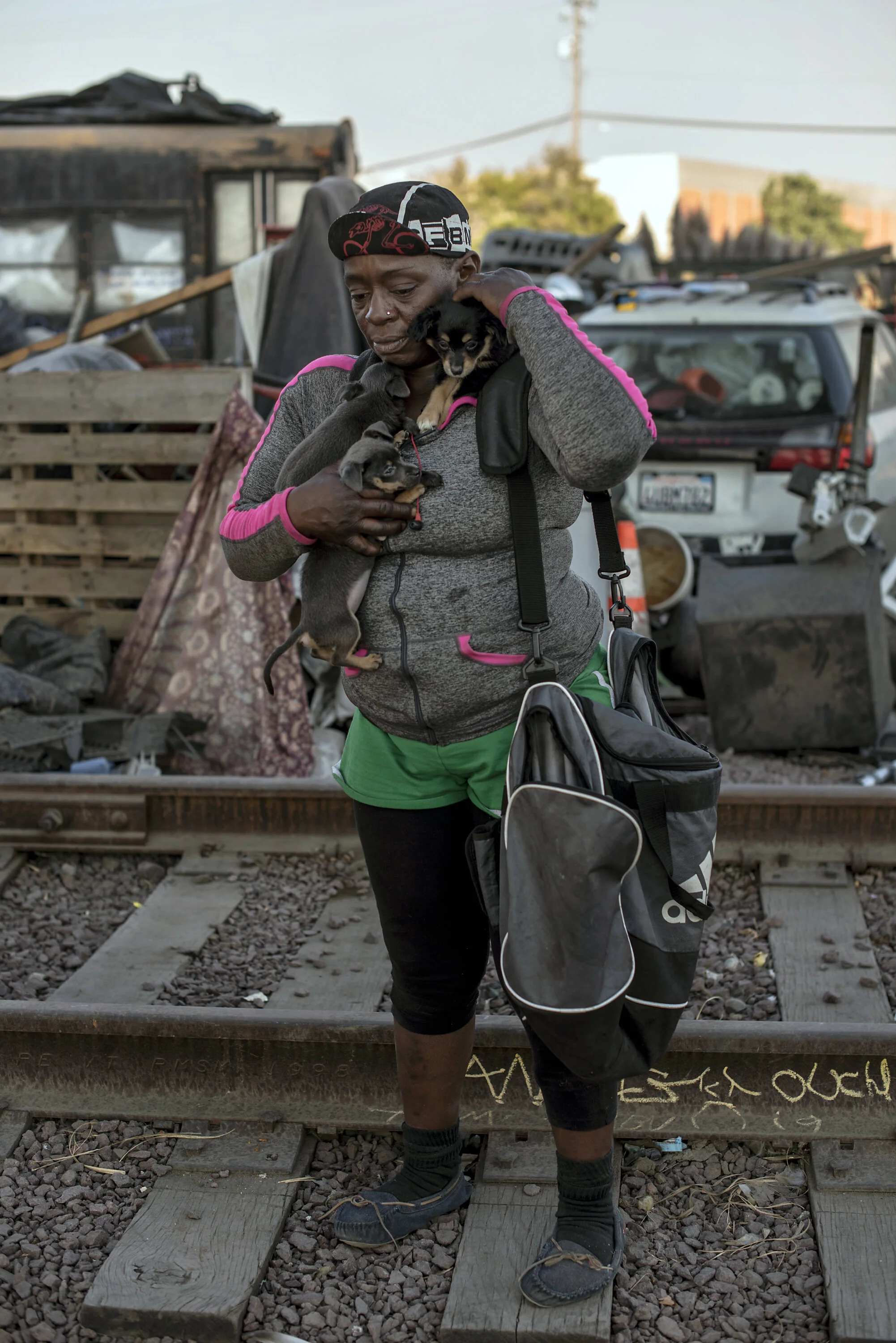  When her dog had a litter of puppies, M became their second mother, as they pile on her for comfort and love.  She stands in front of the vehicle that was her father’s until he died in December.  She will be living there for another week until she b