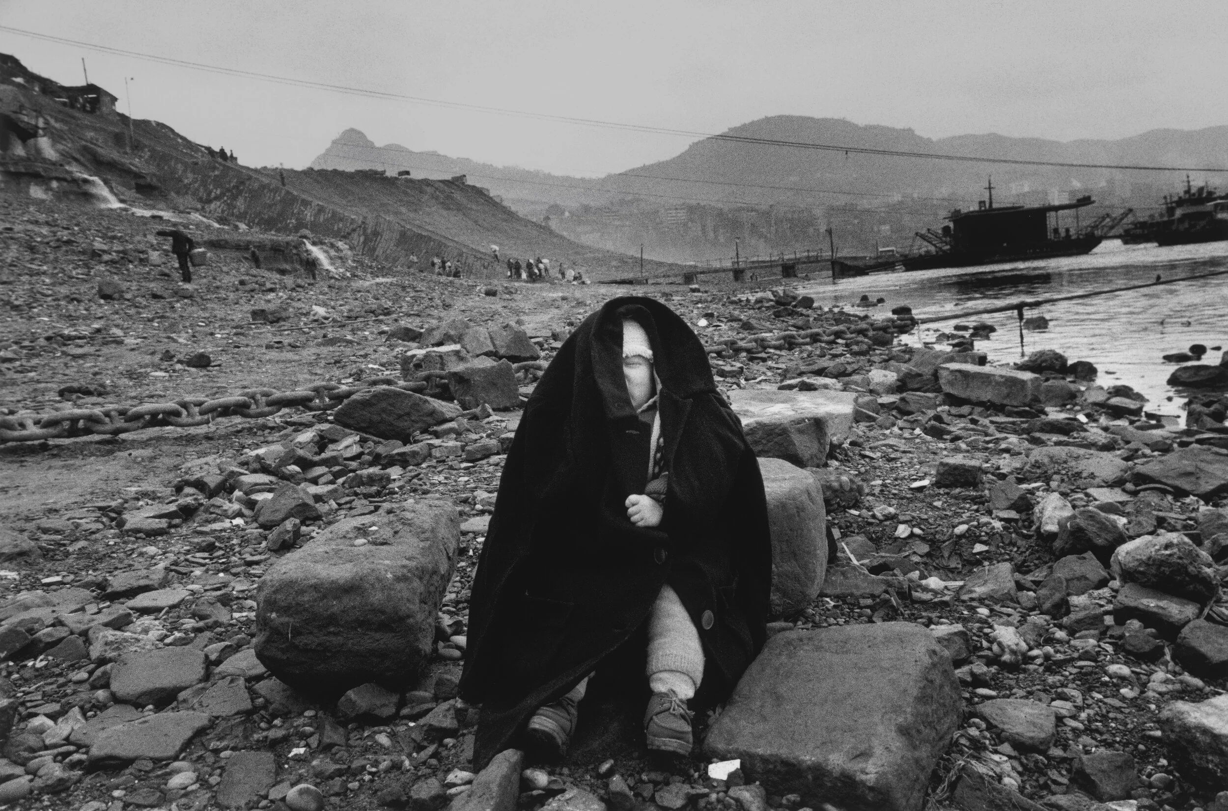  Chongqing, 1993.  Child waits for mother washing clothes on the banks of the Yangtze River which is scheduled to be submerged upon completion of the Three Gorges Dam 