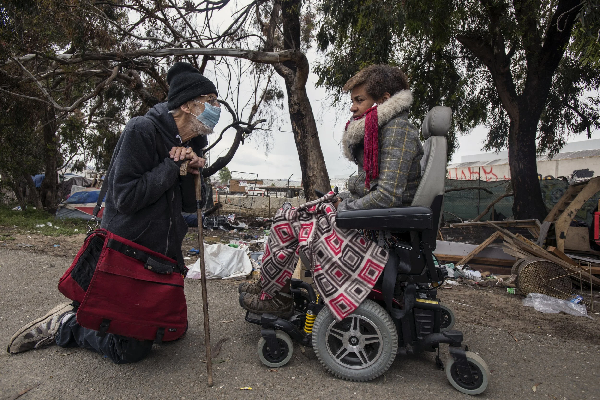  Bay Area Shelter Crisis During Covid . Emeryville, 2021. Activist/lawyer (left) talks with unhoused resident about their lawsuit against the city to get a temporary restraining order preventing eviction of the Ashby/Shellmound freeway exit encampme